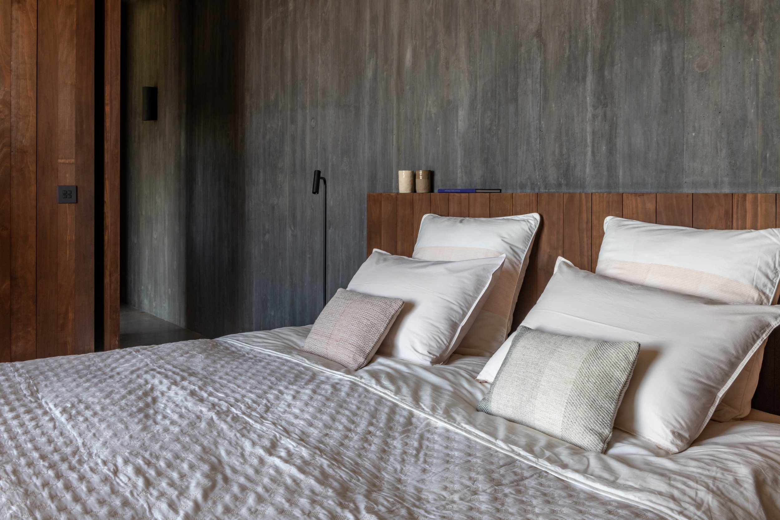 Chambre aux boiseries sombres et lit habillé de lin naturel — hébergement retraite yoga Portugal