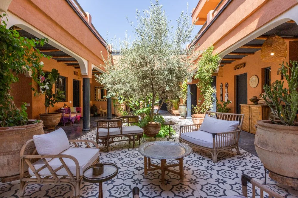 Patio fleuri du riad avec tables dressées — repas végétariens retraite yoga bien-être Marrakech Maroc