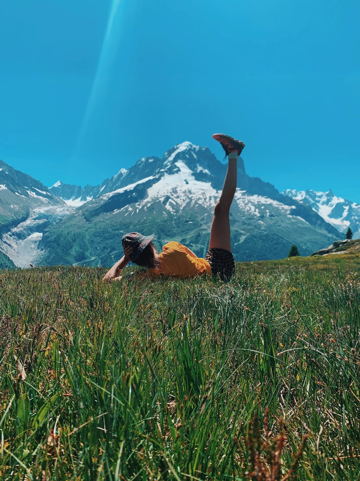 Moment de détente dans l’herbe face aux sommets après une randonnée lors d’une retraite yoga randonnée