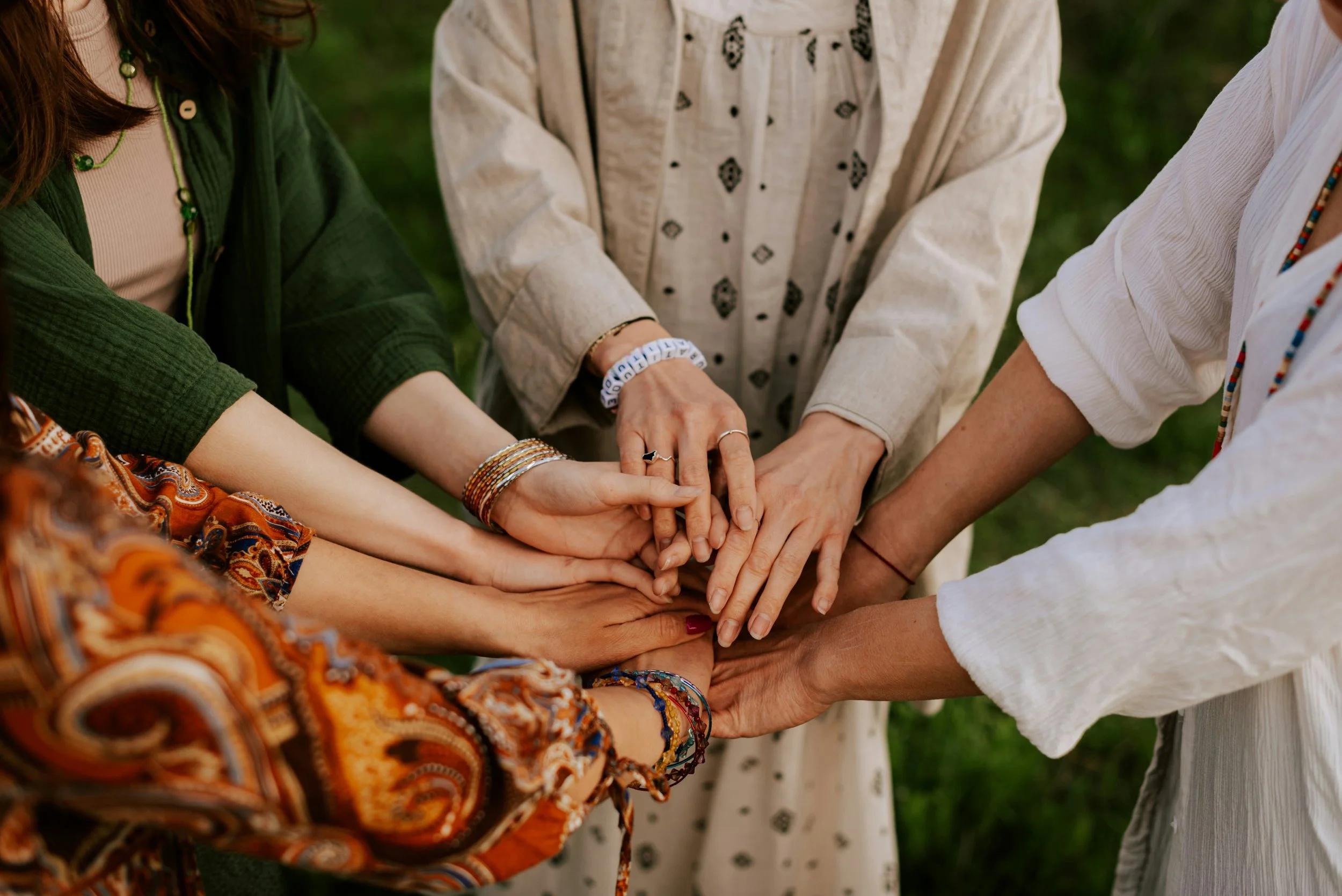 Mains de femmes de tous âges empilées, symbole de sororité et de partage — retraite bien-être en Inde du Sud avec Le Yogascope