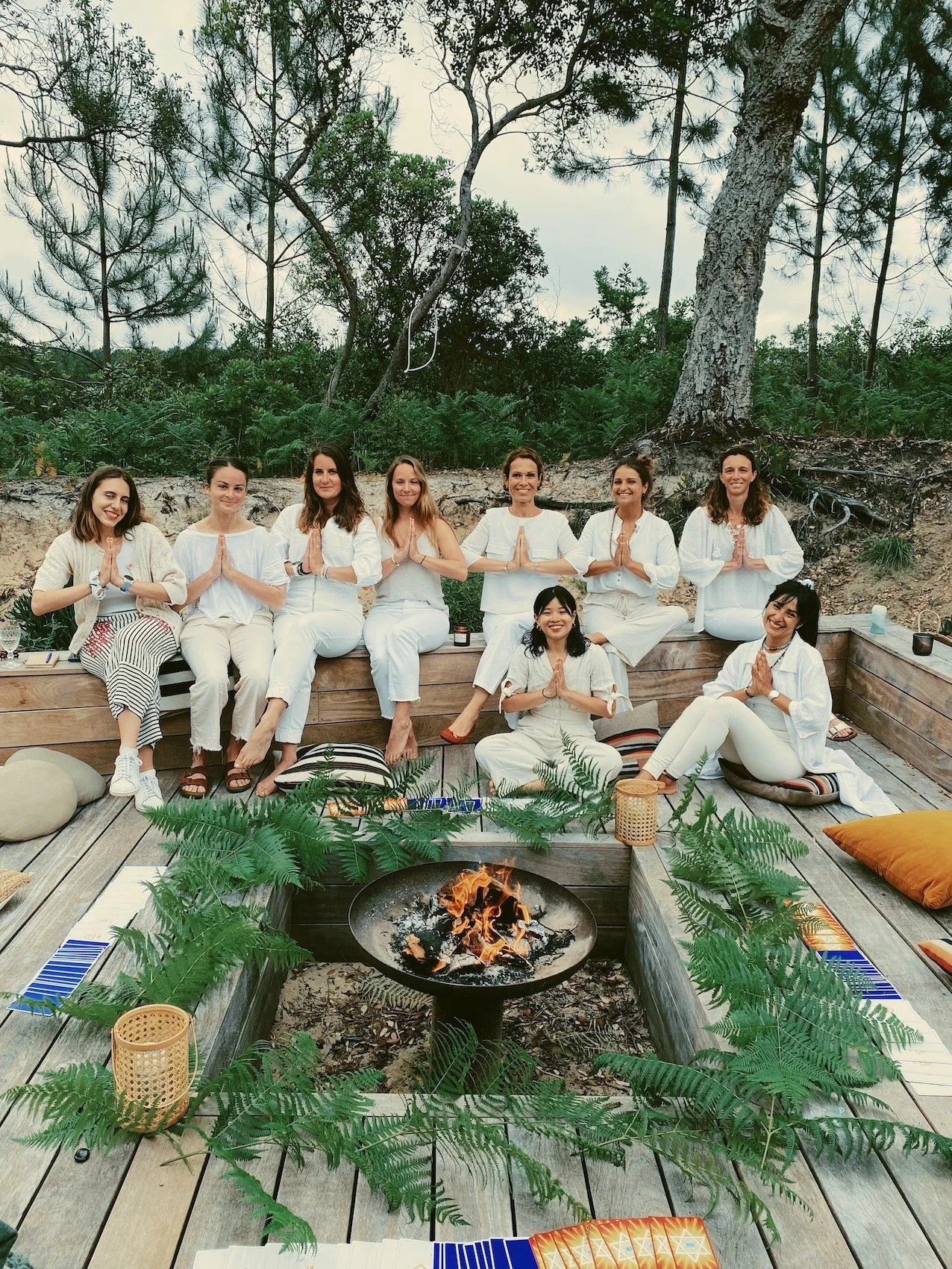 Groupe de femmes en blanc en cercle autour d'un feu de camp dans la pinède landaise, retraite yoga nouvel an original Hossegor