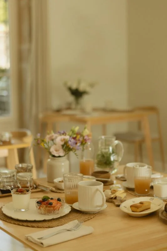 Table de petit déjeuner maison avec jus, fleurs et viennoiseries — pension complète retraite yoga bien-être Bourgogne automne