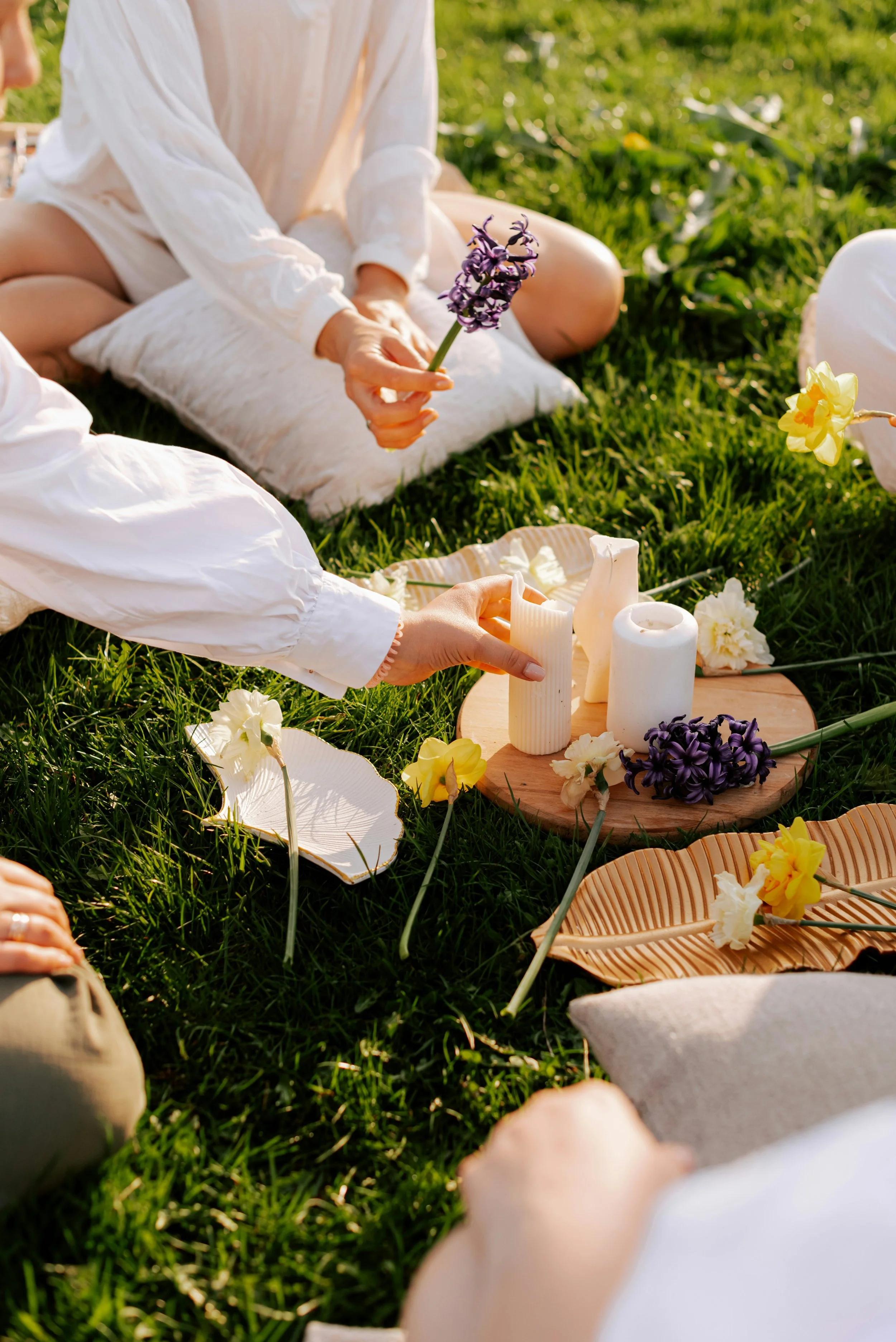 Cercle de femmes dans l'herbe entourées de fleurs et bougies, atelier poésie florale retraite yoga féminin Lacanau