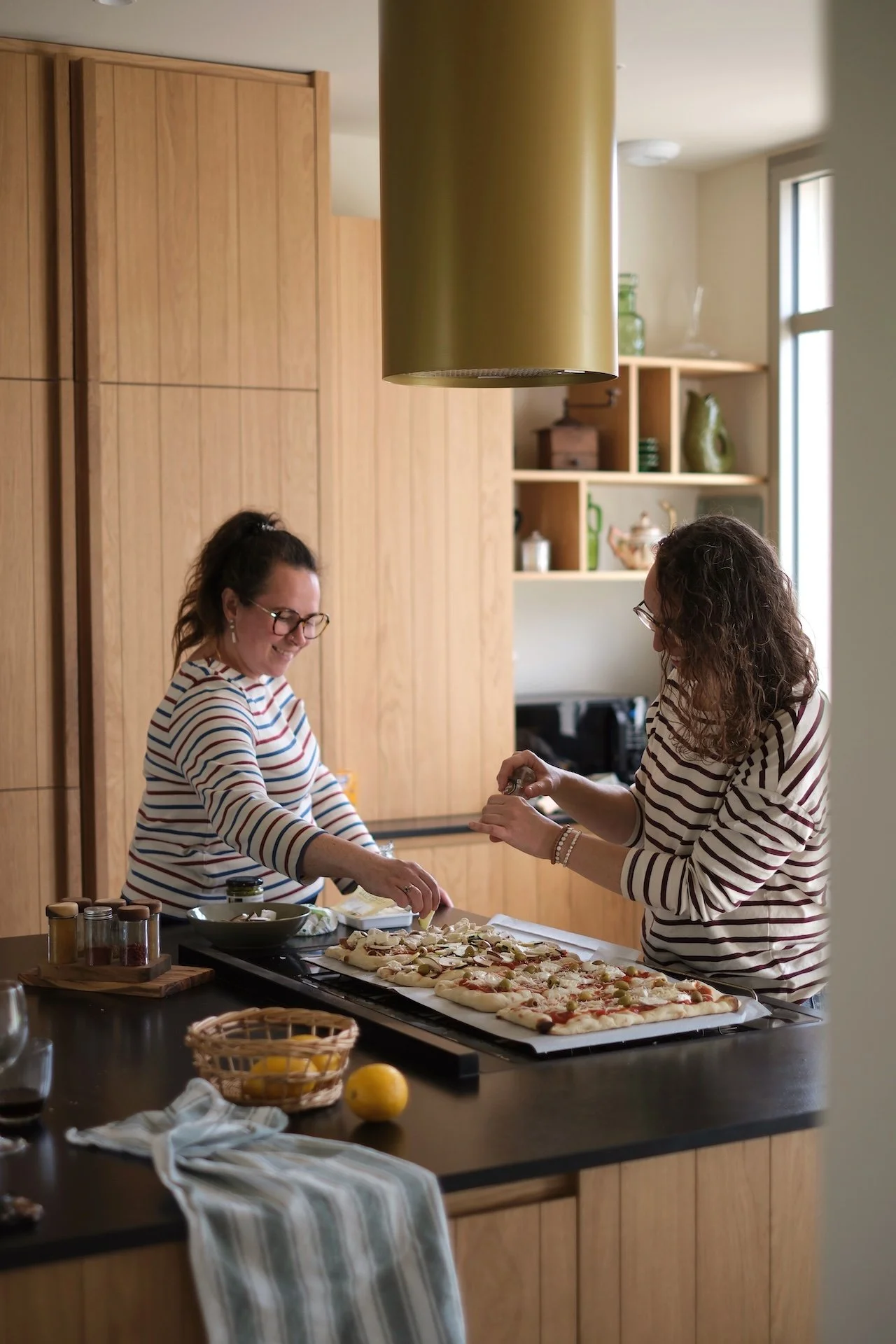 Deux participantes en marinière préparant un repas végétarien dans une cuisine en bois lumineuse — pension complète gourmande en retraite yoga France