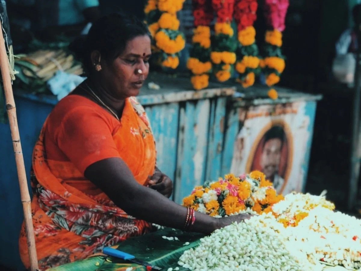 Femme vendant des fleurs et des colliers floraux dans une rue du Kerala — immersion culturelle au cœur de l'Inde du Sud