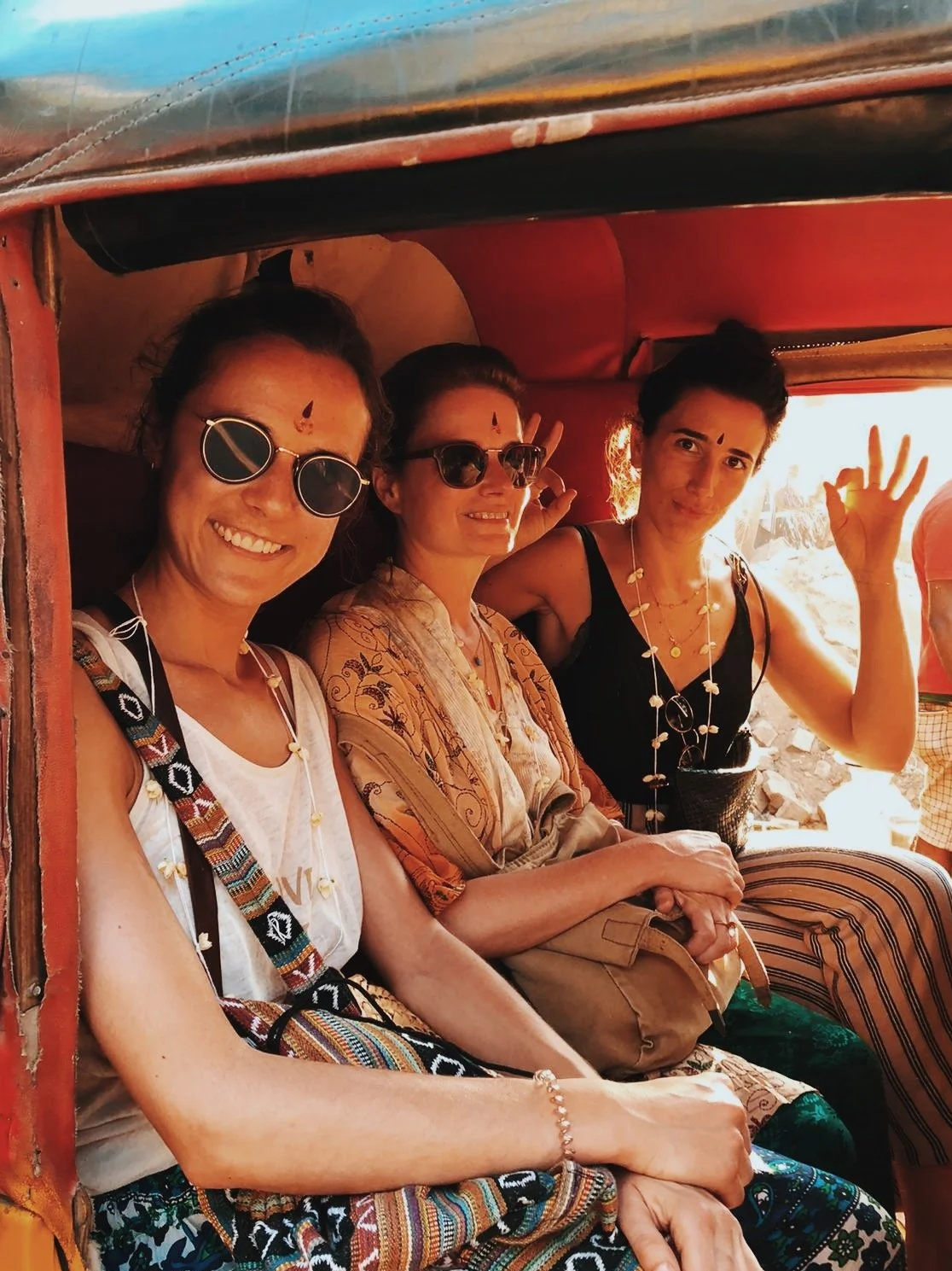 Trois participantes souriantes à bord d'un tuk-tuk, tilak rouge au troisième œil — immersion culturelle et yoga ayurvédique en Inde du Sud