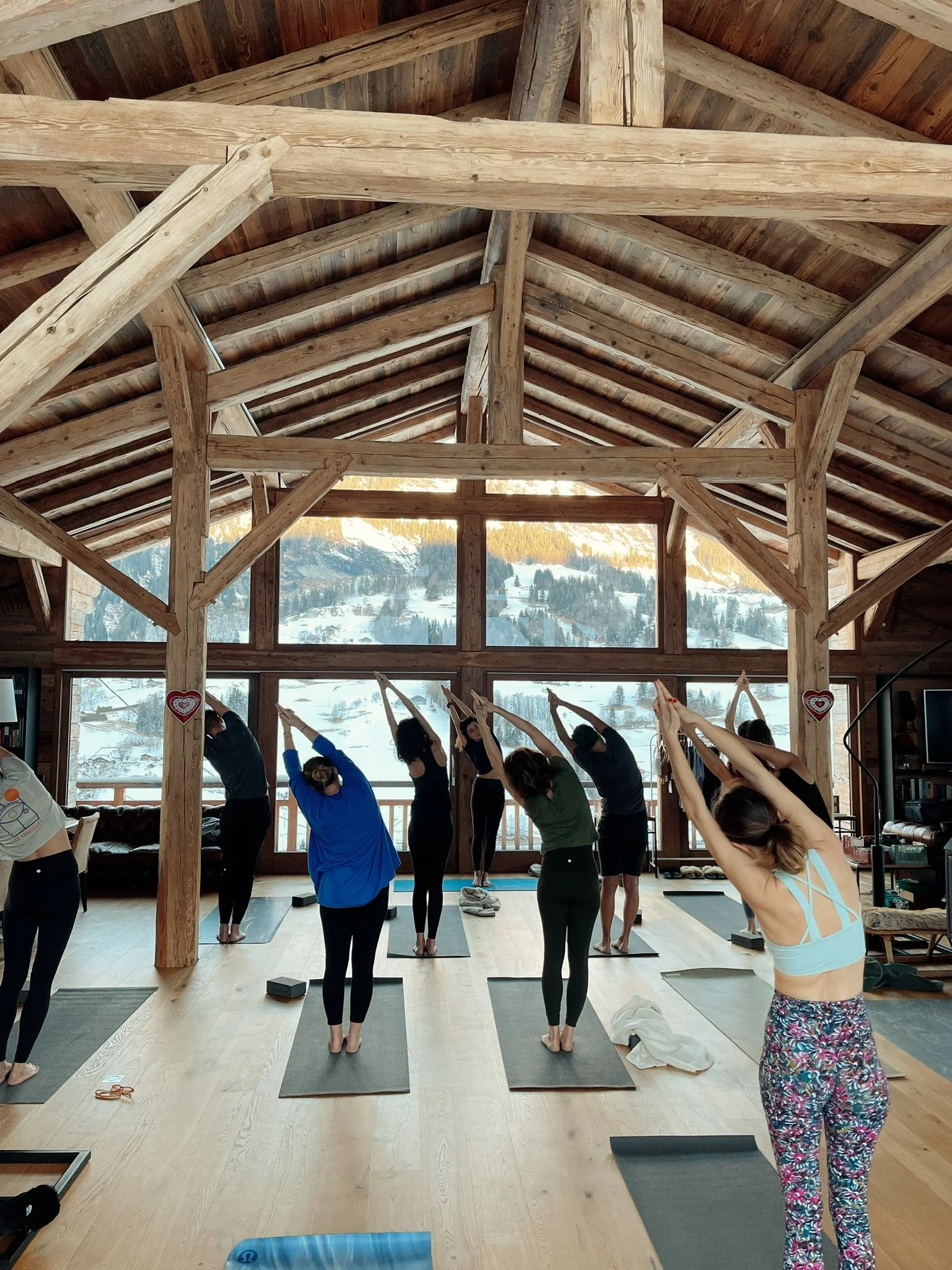 Group yoga session with panoramic view of snow-capped mountains.