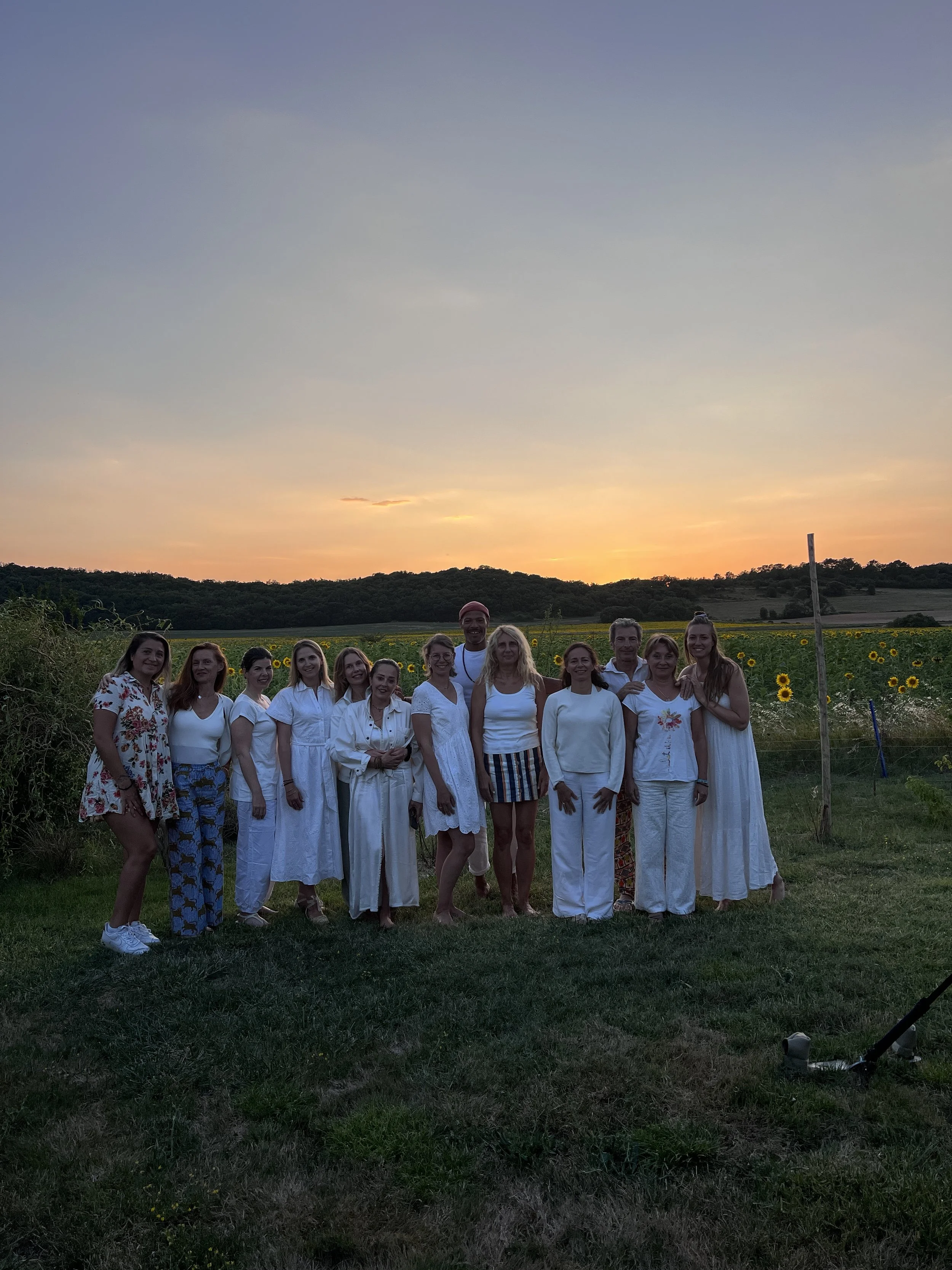 Groupe en tenue blanche lors d'un cercle au coucher du soleil - retraite yoga bien-être Provence