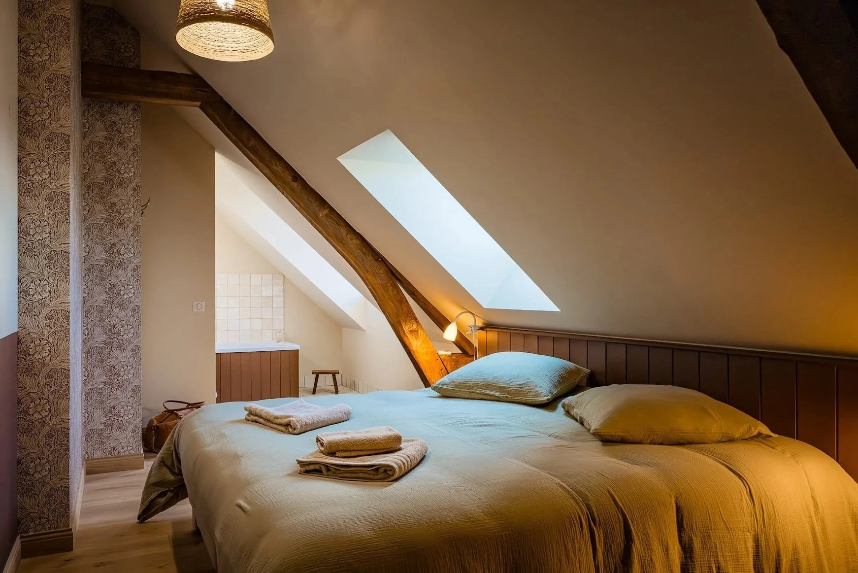 Chambre privative standard sous les toits, salle de bain ouverte avec baignoire, tons beige et vert doux — intimité et charme d'une retraite bien-être à la campagne