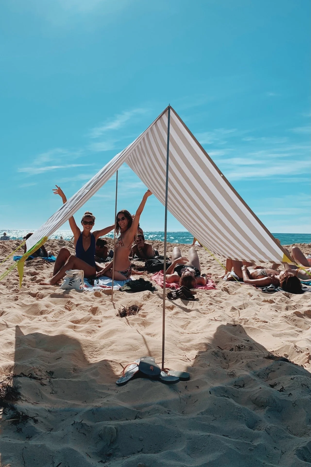 Participantes installées sous un tipi rayé beige face à la mer du Nord — rituel en bord de mer lors d'une retraite yoga été en Baie de Somme