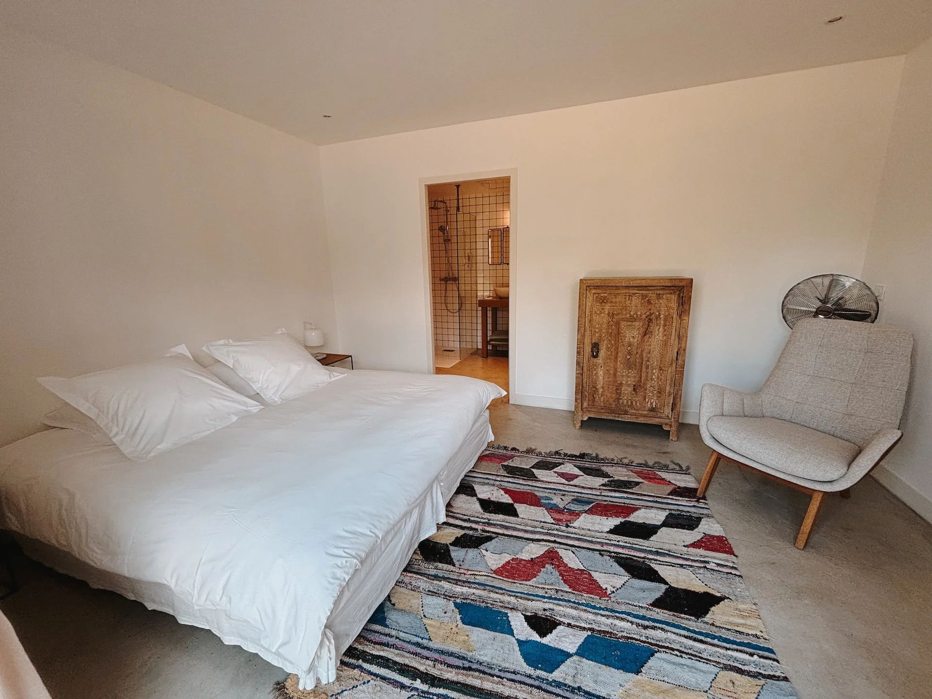 Chambre double épurée avec tapis berbère et commode en bois — hébergement retraite yoga Kundalini château de Solterre proche de Paris