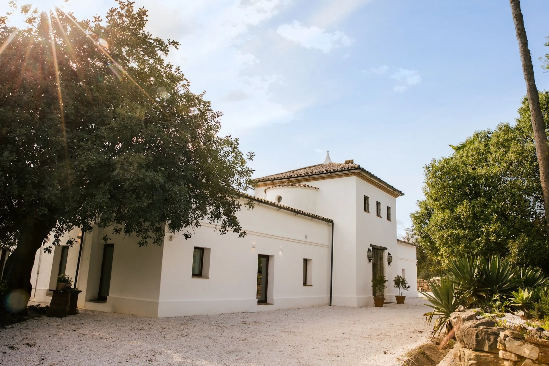 Façade blanche du cortijo andalou avec allée gravillonnée — séjour yoga premium Espagne août 2026