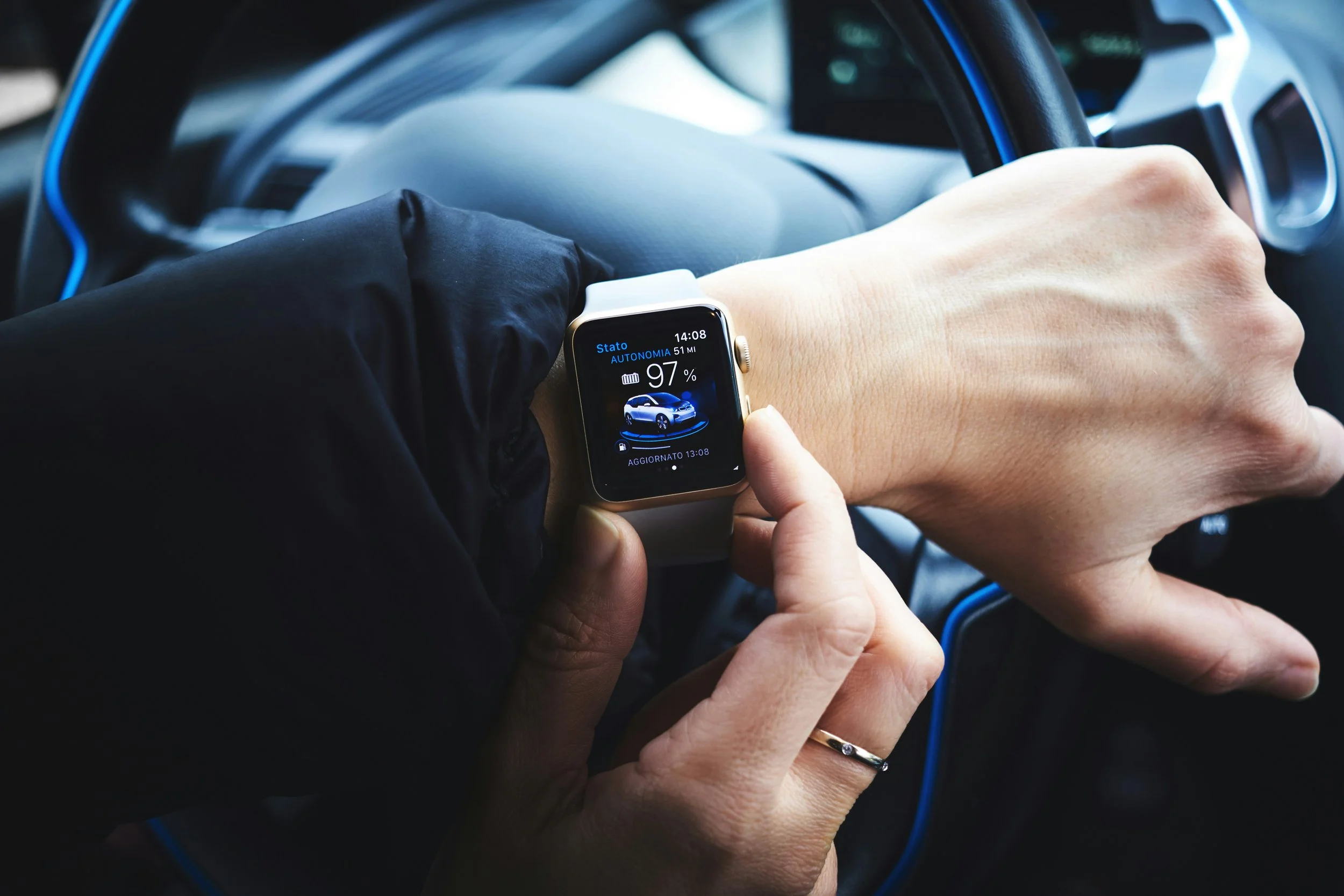 Close-up of a person using a smartwatch while sitting in a car. The watch displays vehicle information, illustrating how wearable technology can connect with other devices and provide information on the go.