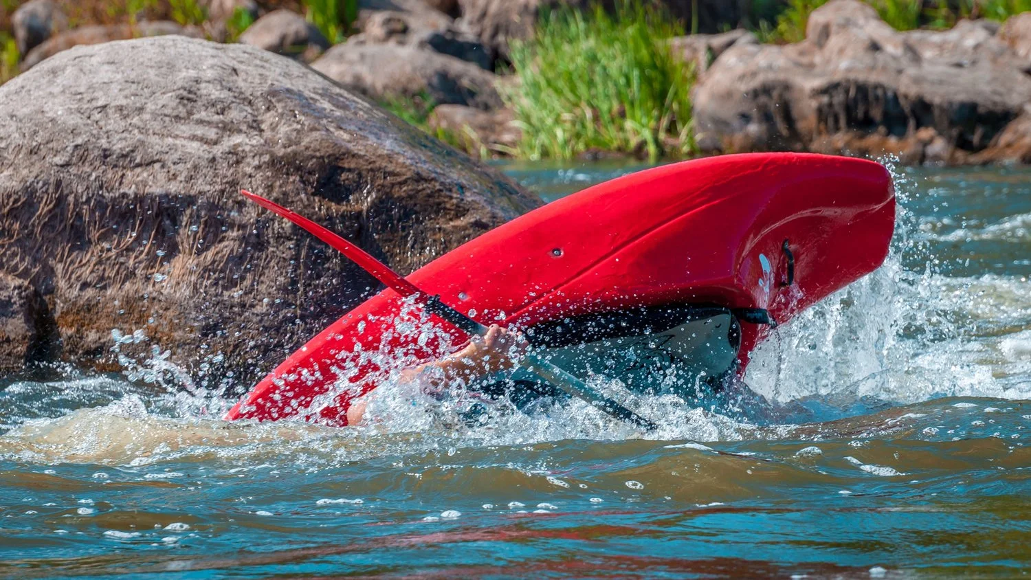 White water kayaker rolling up on a lake.