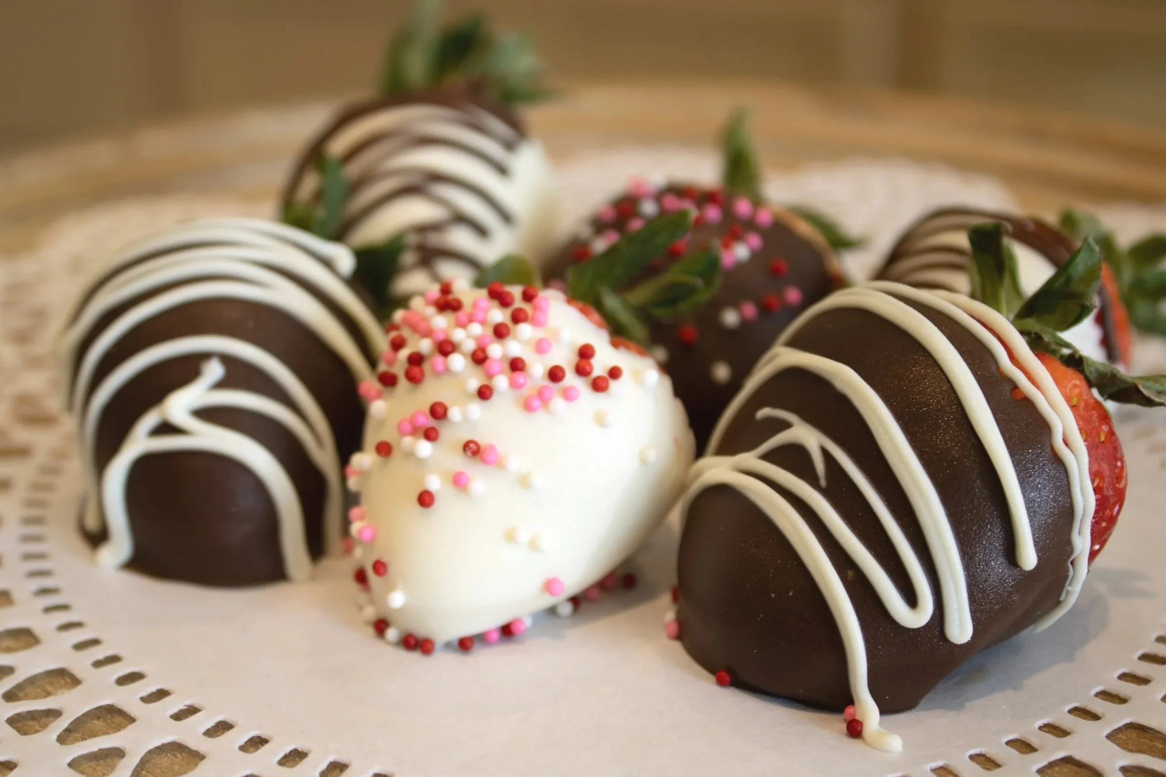 Strawberries dipped in chocolate with white and pink sprinkles, decorated for Valentine's Day.