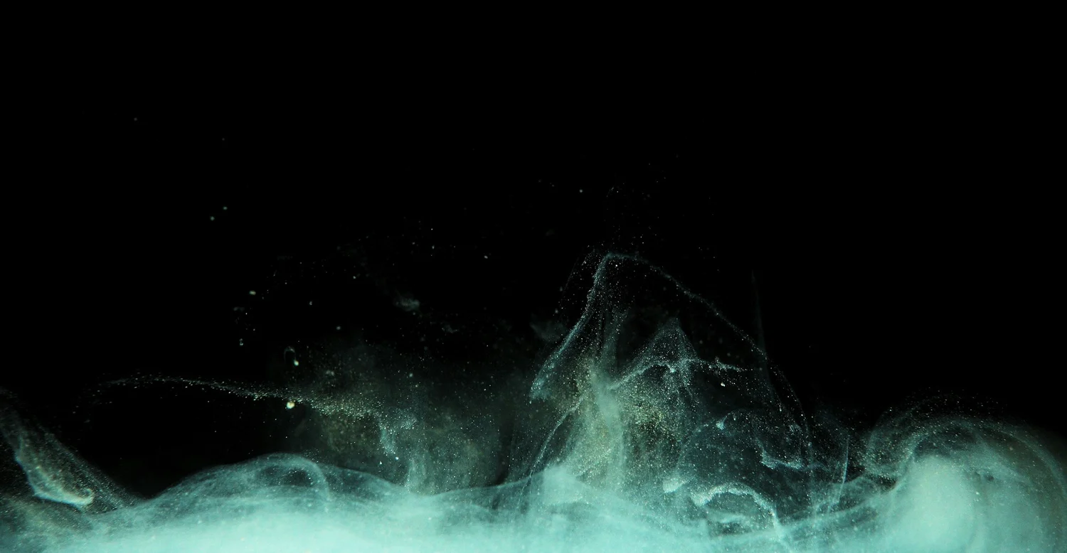 Teal ink dispersing in water in smooth laminar filaments