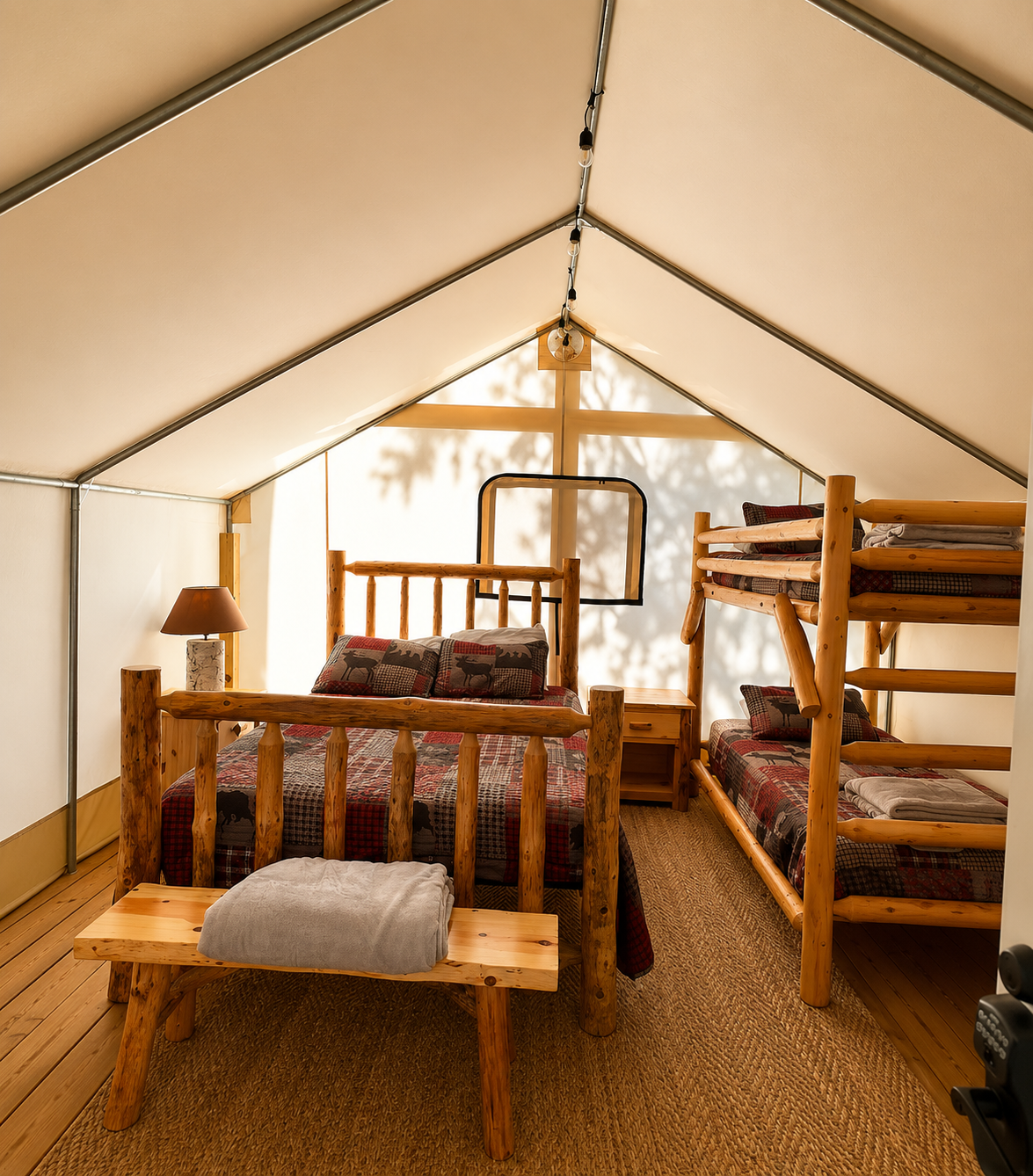 Cozy glamping tent interior with a queen bed and modern furnishings at Raging River Resort in Marquette, Michigan.