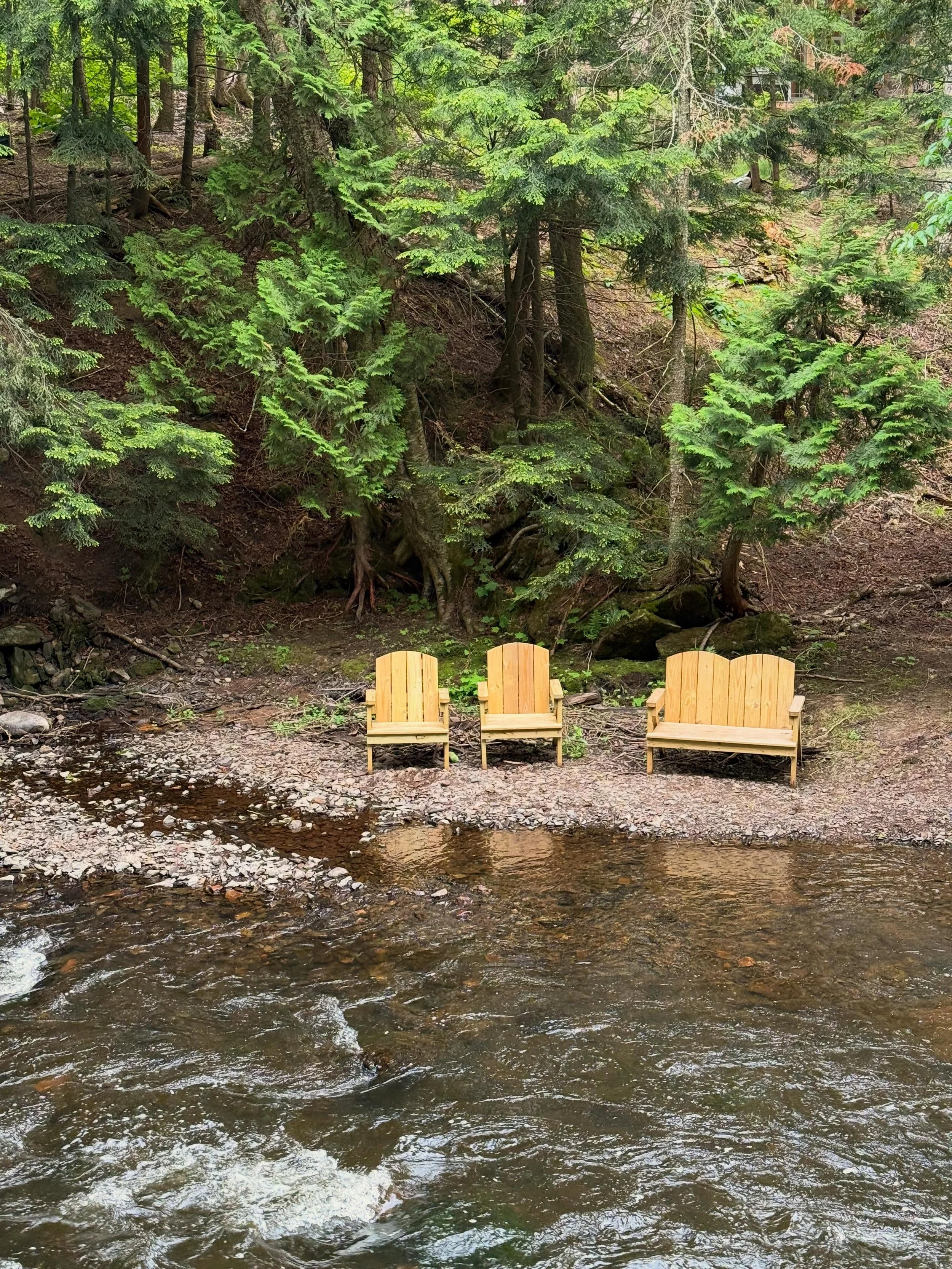 Adirondack chairs placed in the river at Raging River Resort in Marquette