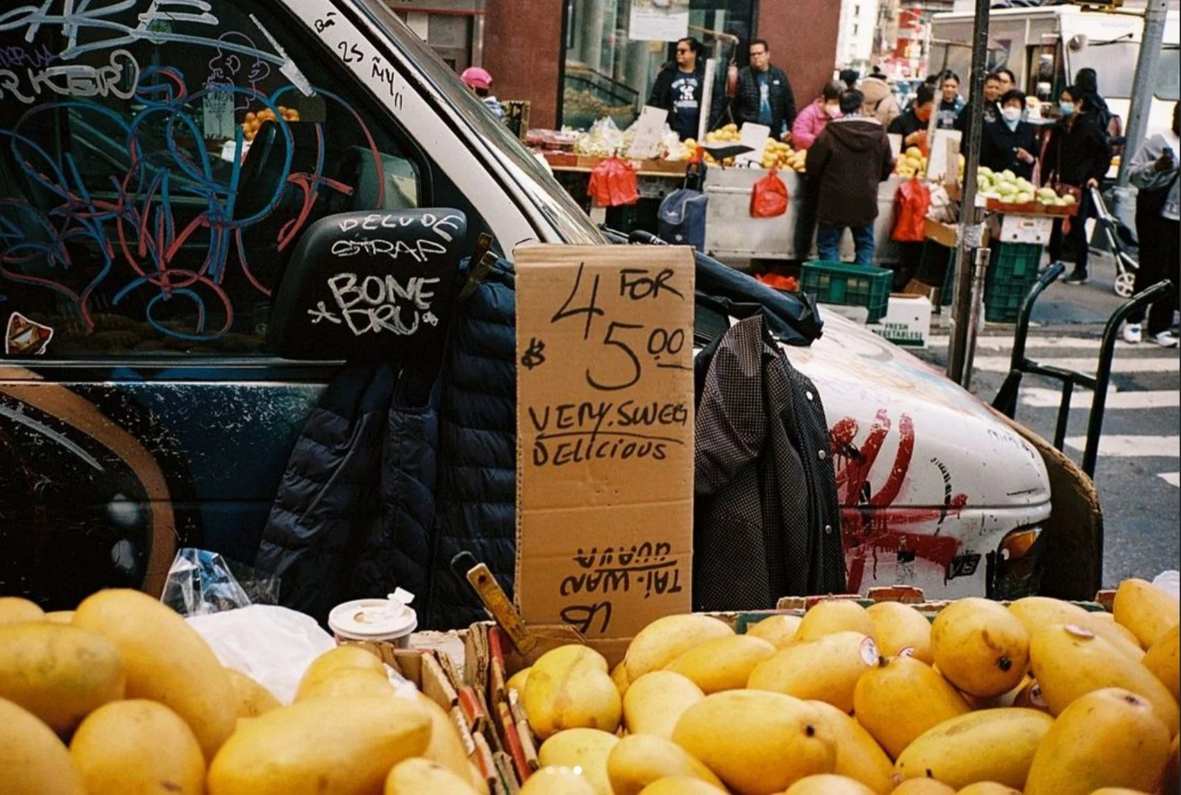 Fruit displayed at a street market stall beside a handwritten price sign.
