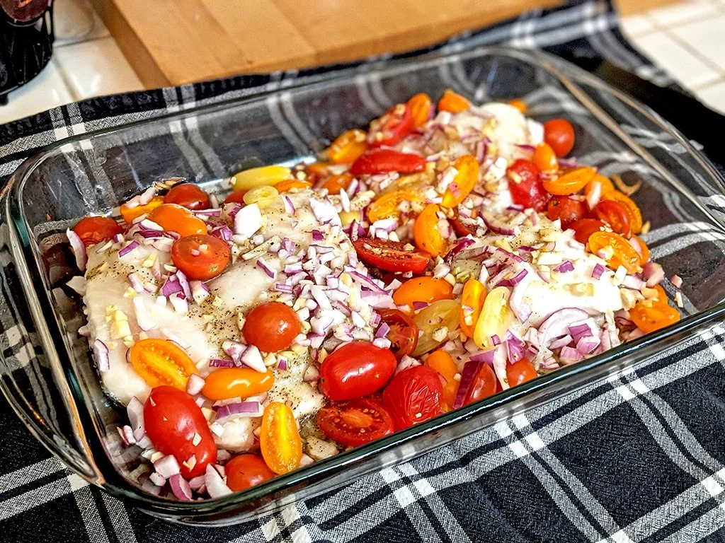 Healthy baked fish with cherry tomatoes, red onion, and herbs for recovery-focused nutrition