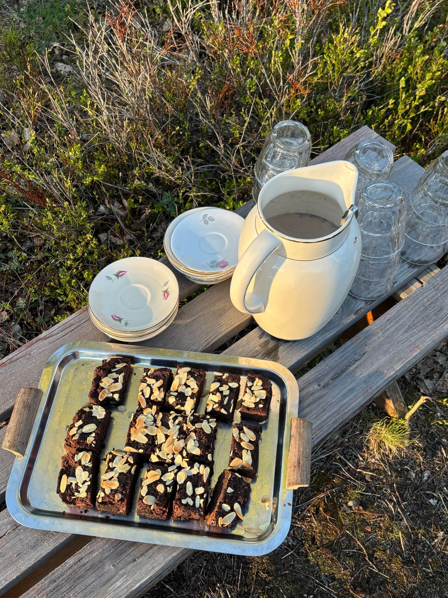 Assorted ingredients for baking or cooking, including chopped strawberries on a baking sheet, bowls of chocolate, nuts, and peanut butter, on a wooden table.