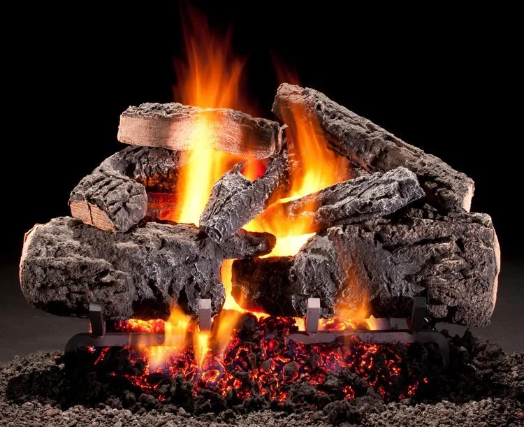 Artificial burning fire logs with bright orange flames and glowing embers, placed on a metal grate.