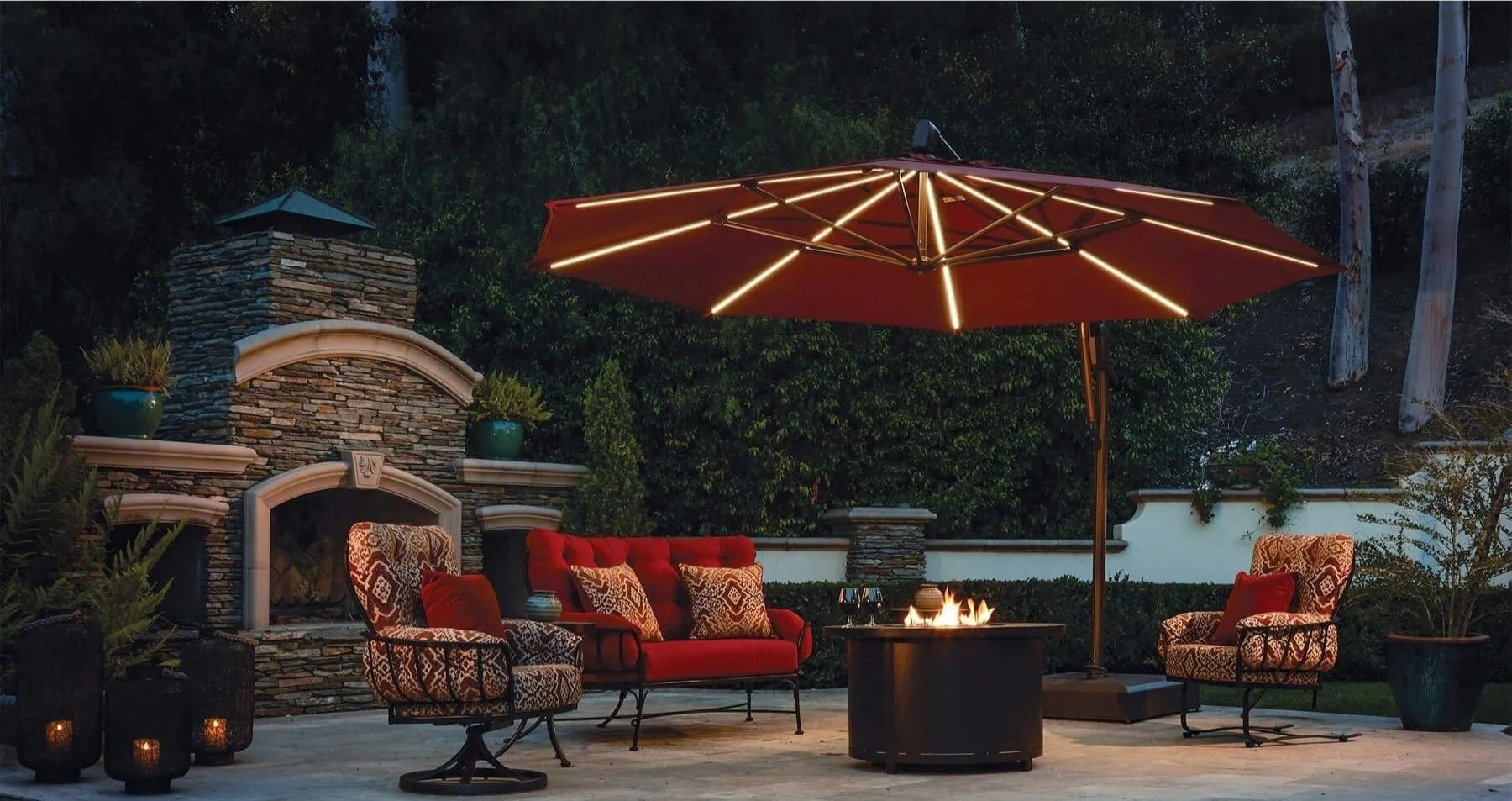 Outdoor patio with red umbrella, stone fireplace, chairs, and fire pit