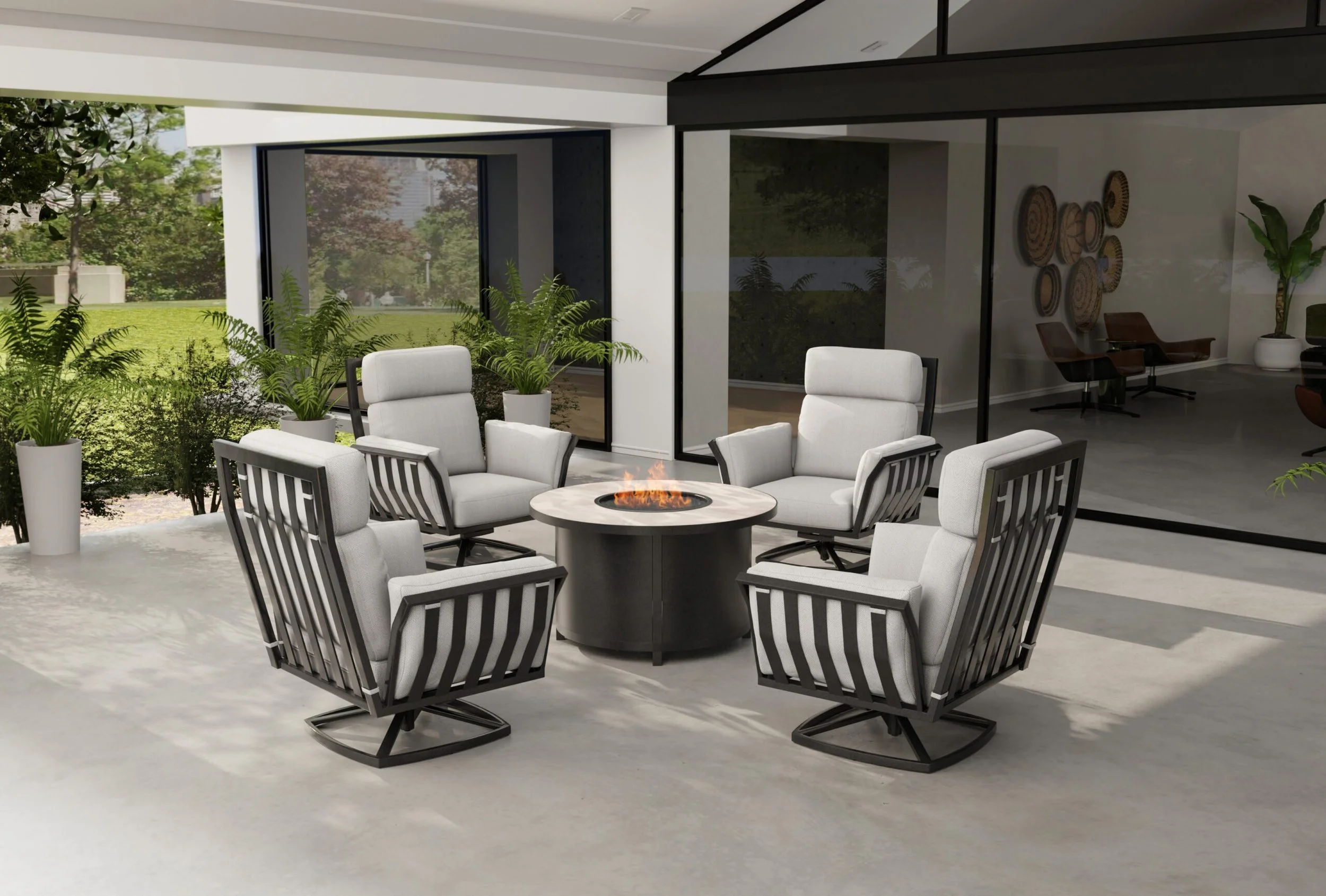 Modern patio with four cushioned chairs around a round fire pit, surrounded by greenery and glass doors leading to an indoor space.