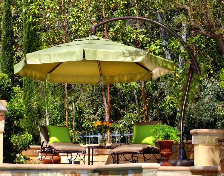 Outdoor patio with green umbrella, cushioned chairs, and plants