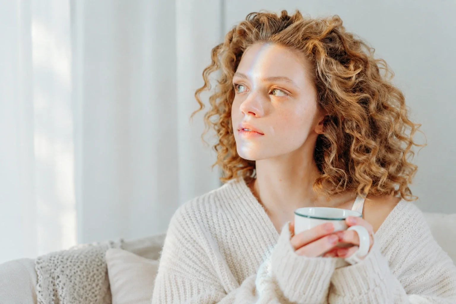 A young looking thoughtfully to the side in a softly lit room