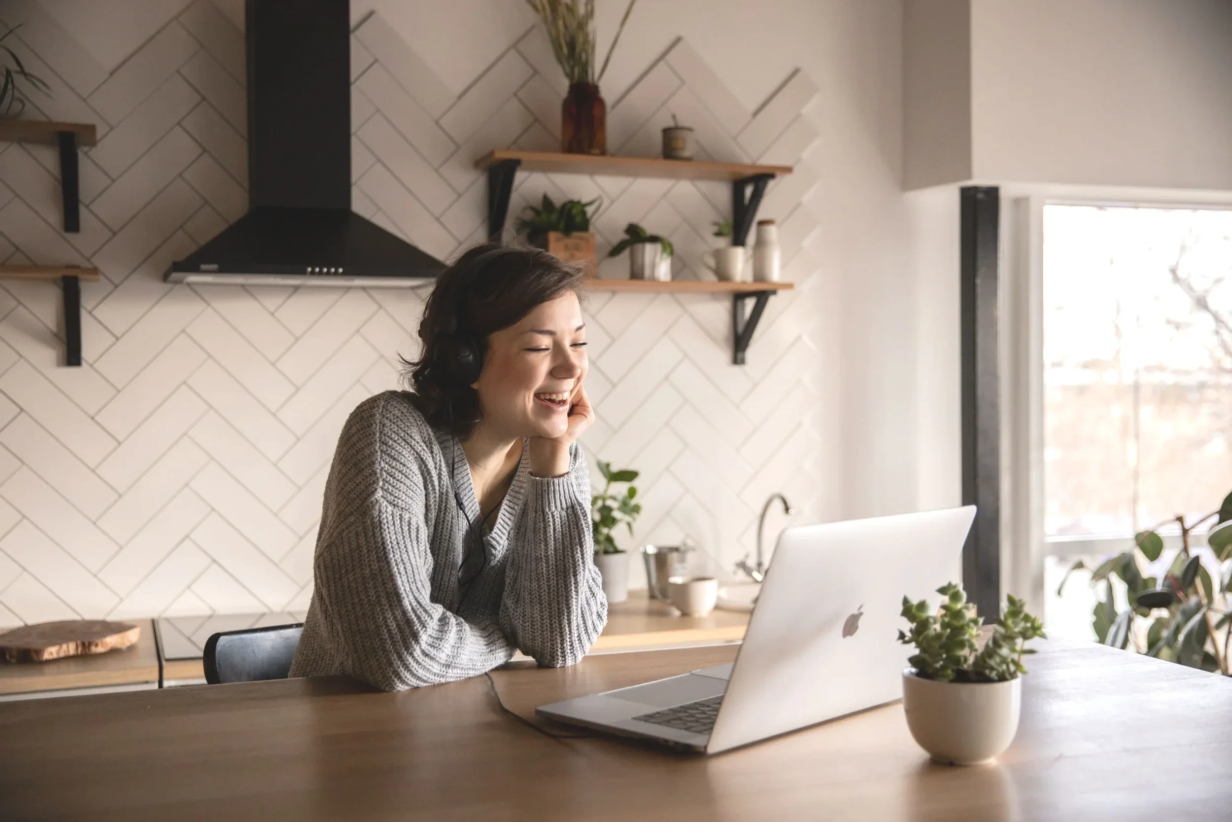 Women sitting at her kitchen counter on her laptop smiling during her free therapy consultation.