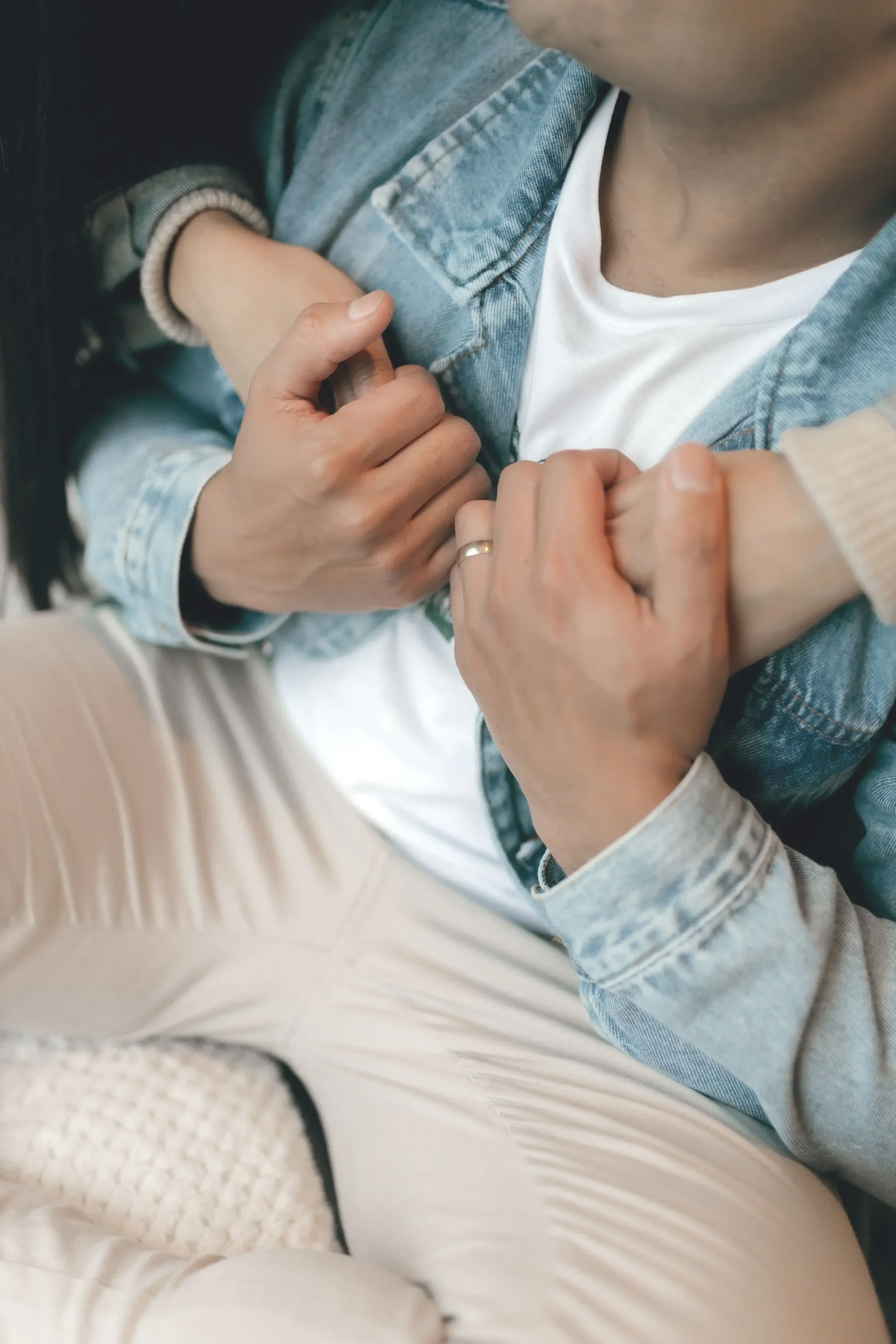 A women hugging her male partner from behind while her partner holds her hands against his chest, reconnecting. Feeling emotionally safe together.
