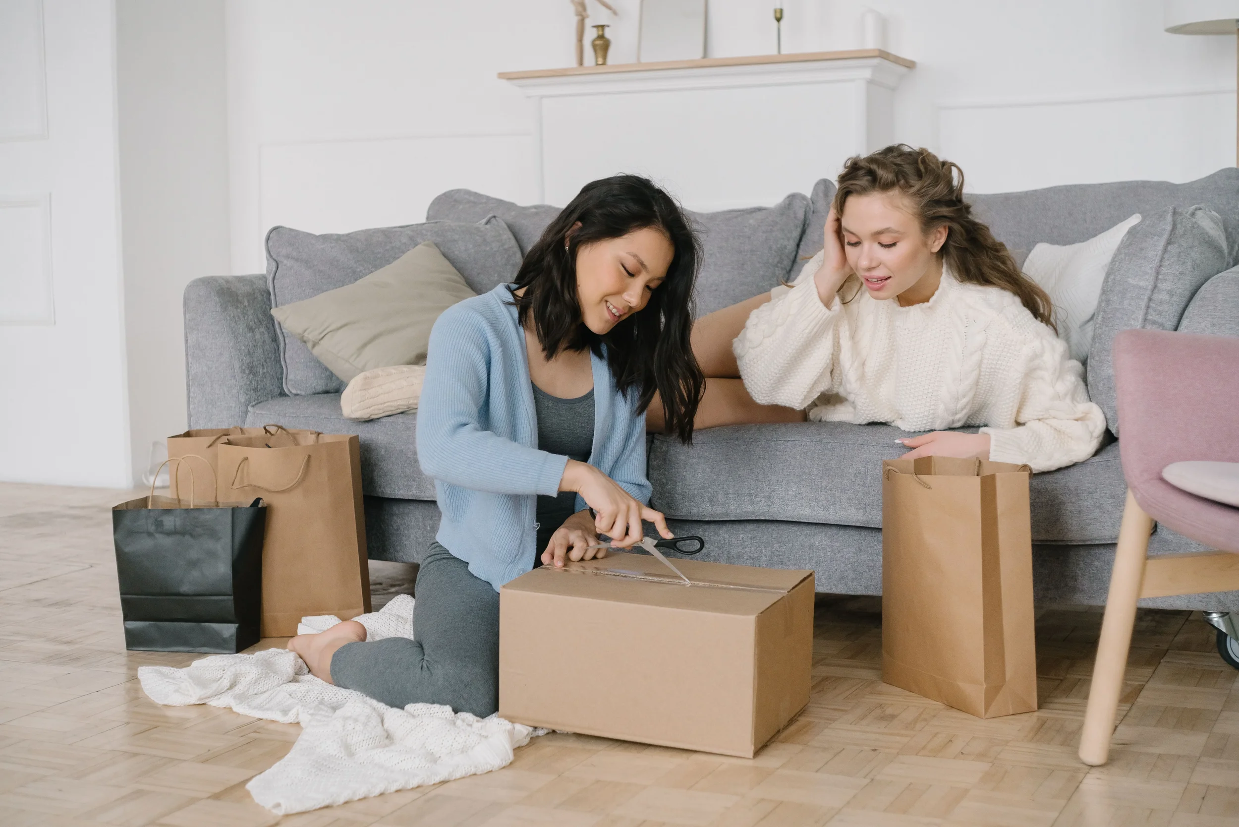 Two women sitting in living room packing boxes and discussing boundaries