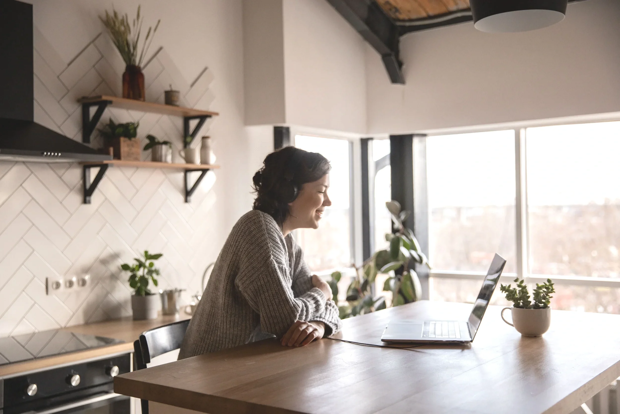 Women sitting at her kitchen counter looking contently at her computer during her consultation with a Welcoming Home Psychotherapy in Toronto.