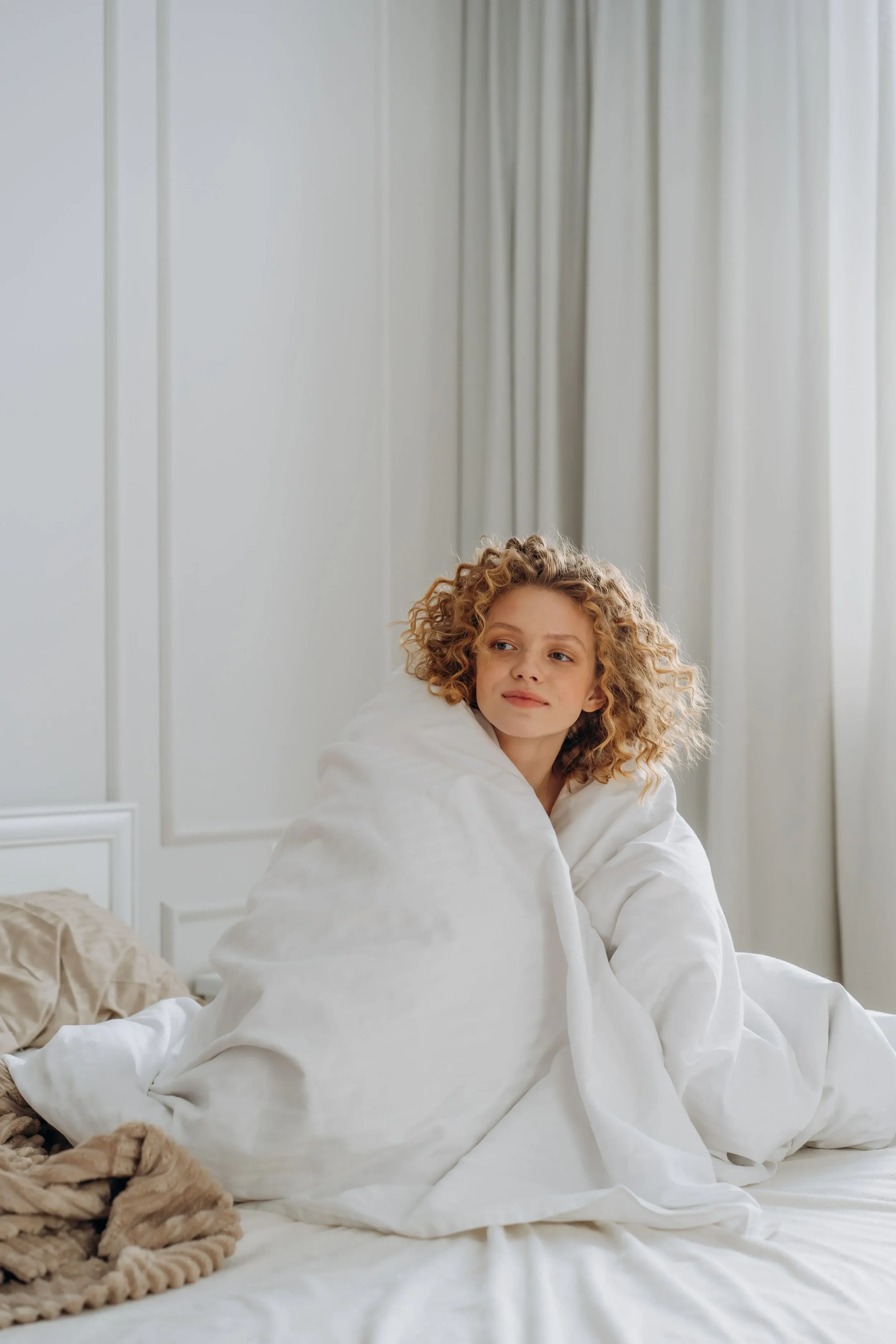 Women sitting in bed with the blanket wrapped around her ready to make a change and reduce her decision fatigue. Looking optimistic and hopeful around her availability to change.