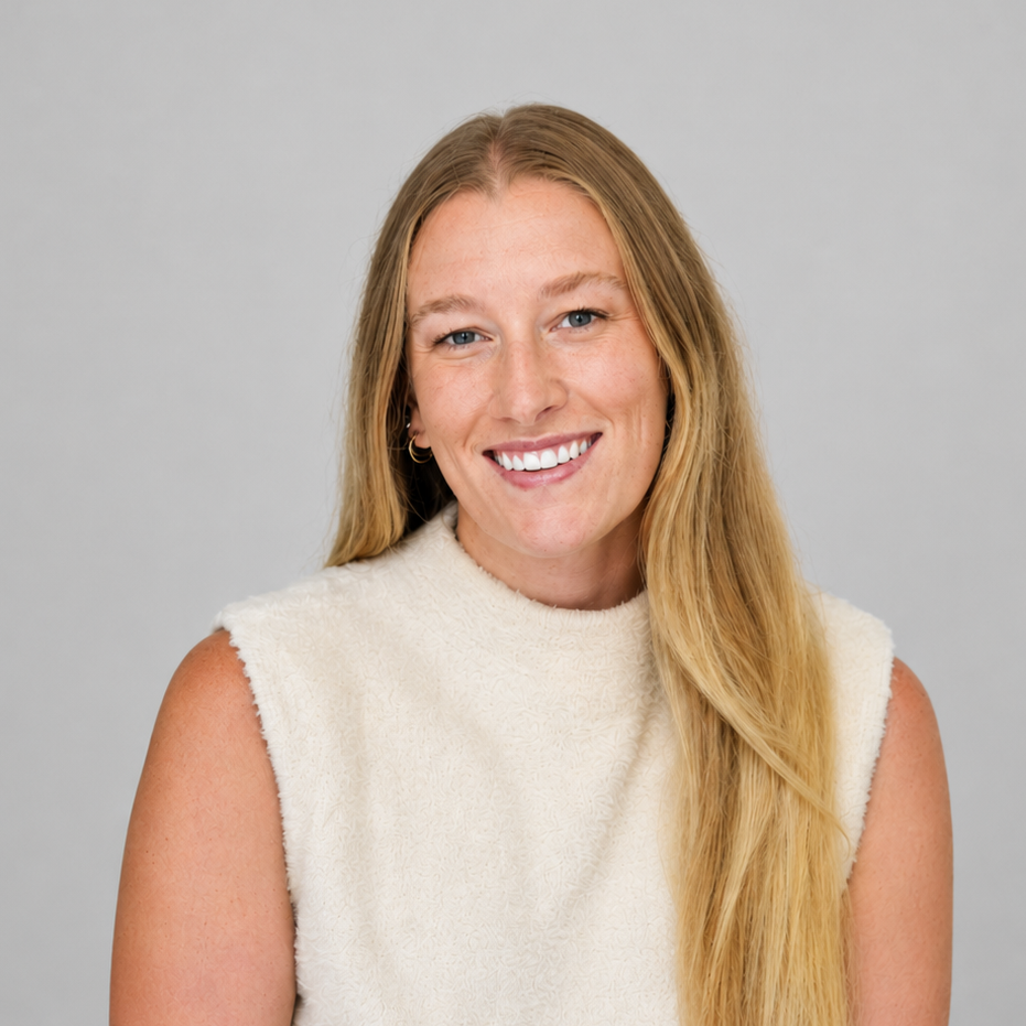 A young woman with long blonde hair, wearing a sleeveless off-white top, smiling against a light gray background.