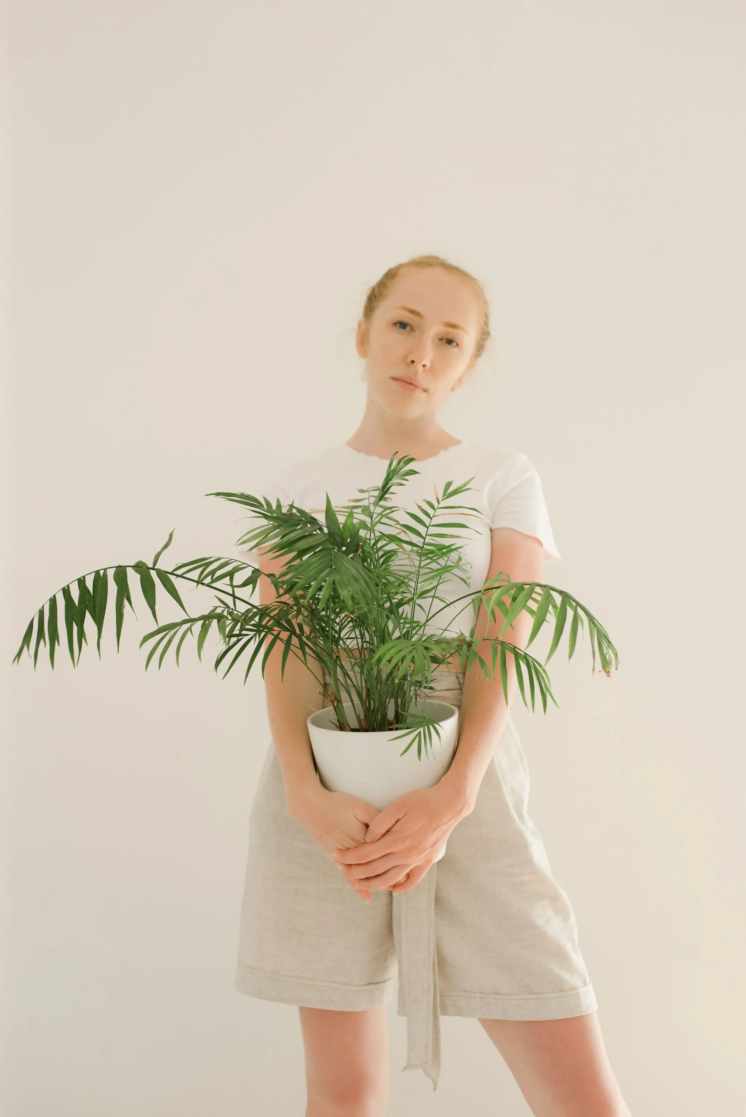 Women holding a potted plant in front of her showing her face. Representing how much she has grown as a person.