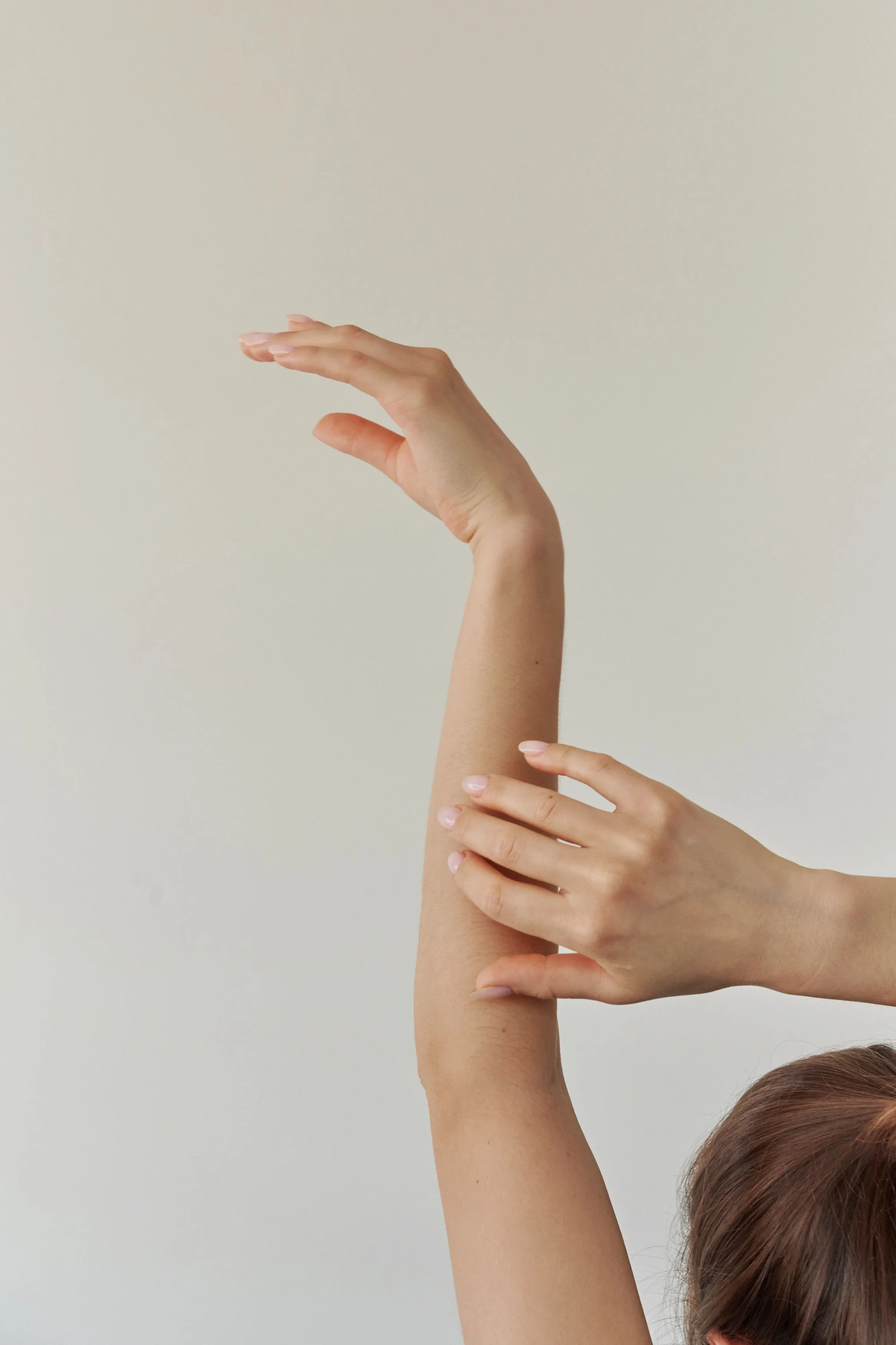 A person's hand reaching upward with fingers extended, touching another person's arm.