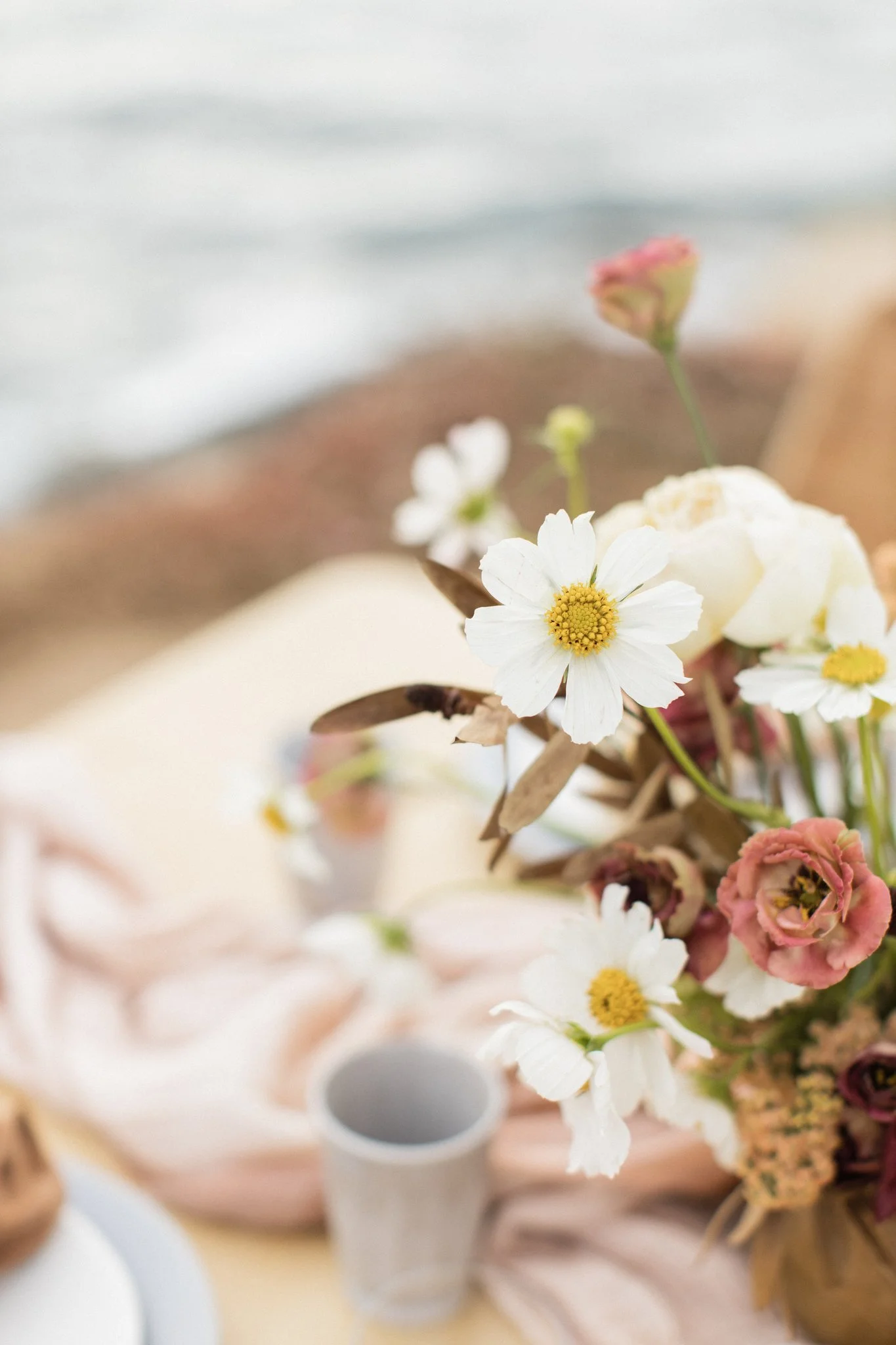 Close-up of a flower arrangement with white and pink flowers on a table, blurred background.