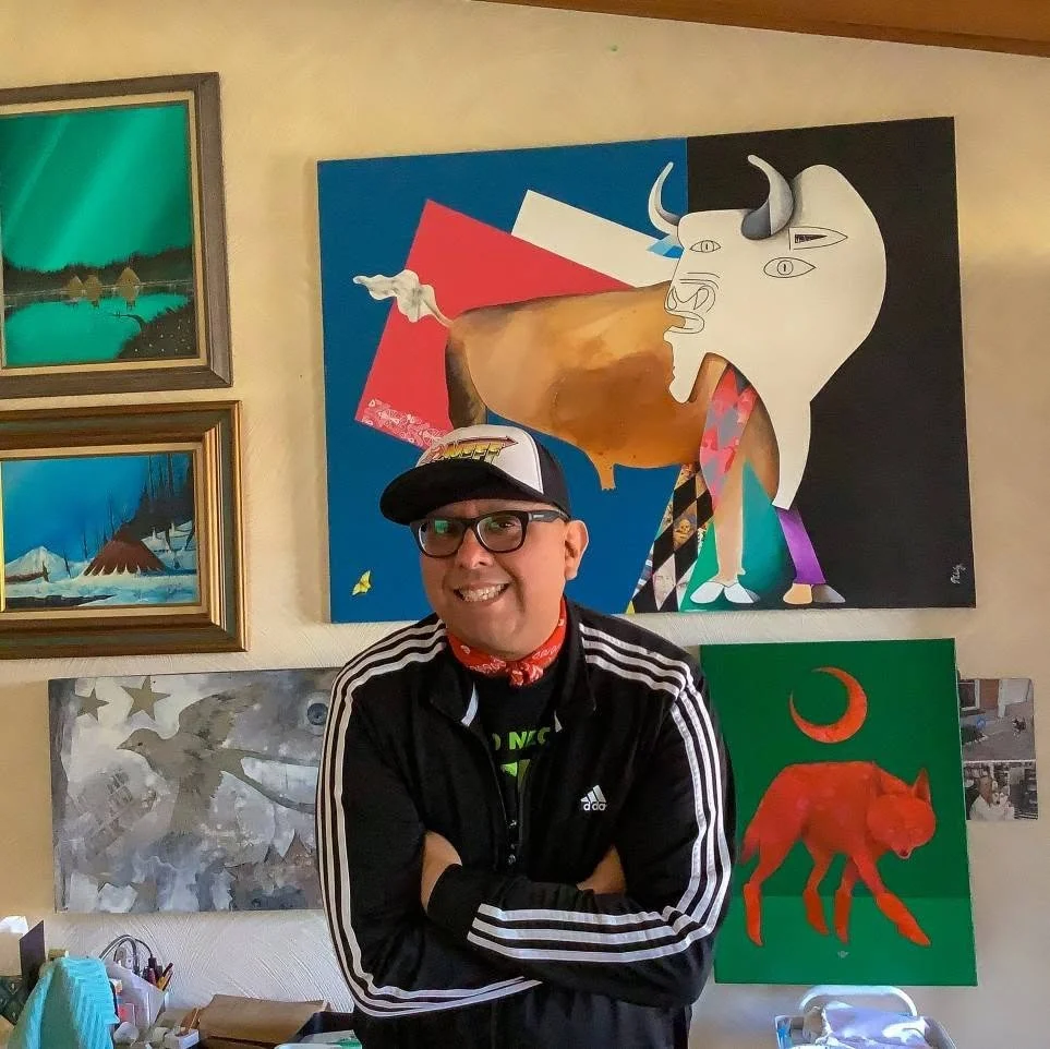 Micah Wesley stands with his arms folded in front of his paintings at a gallery