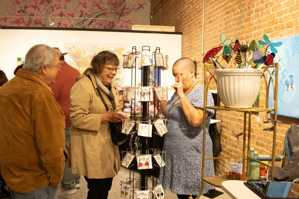 A vendor during Punk Rock Santa Flea market talking with guests inside the Uncanny Art House gallery