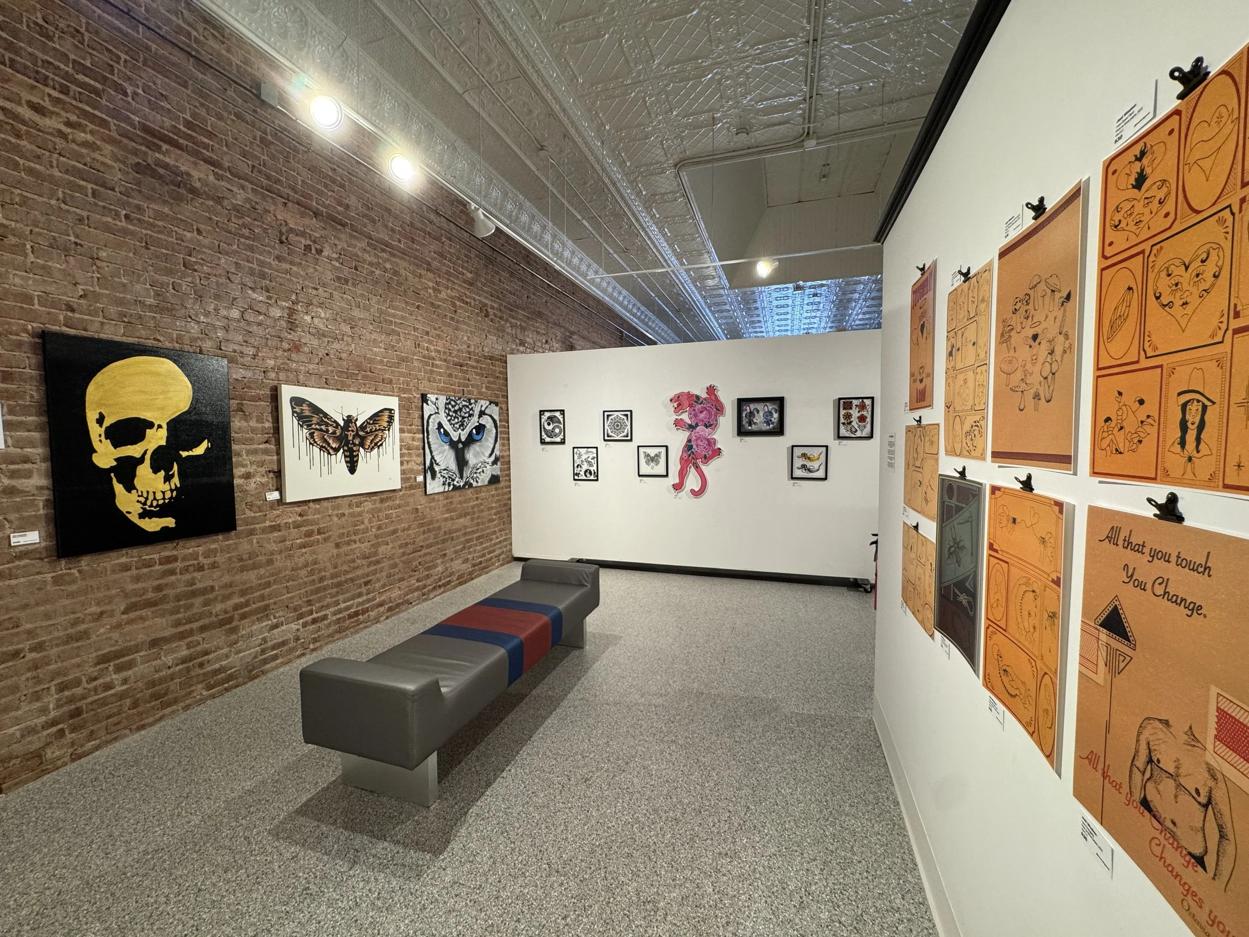 A man and woman talking in an art gallery, with a white sculpture of a dancing figure in the background.