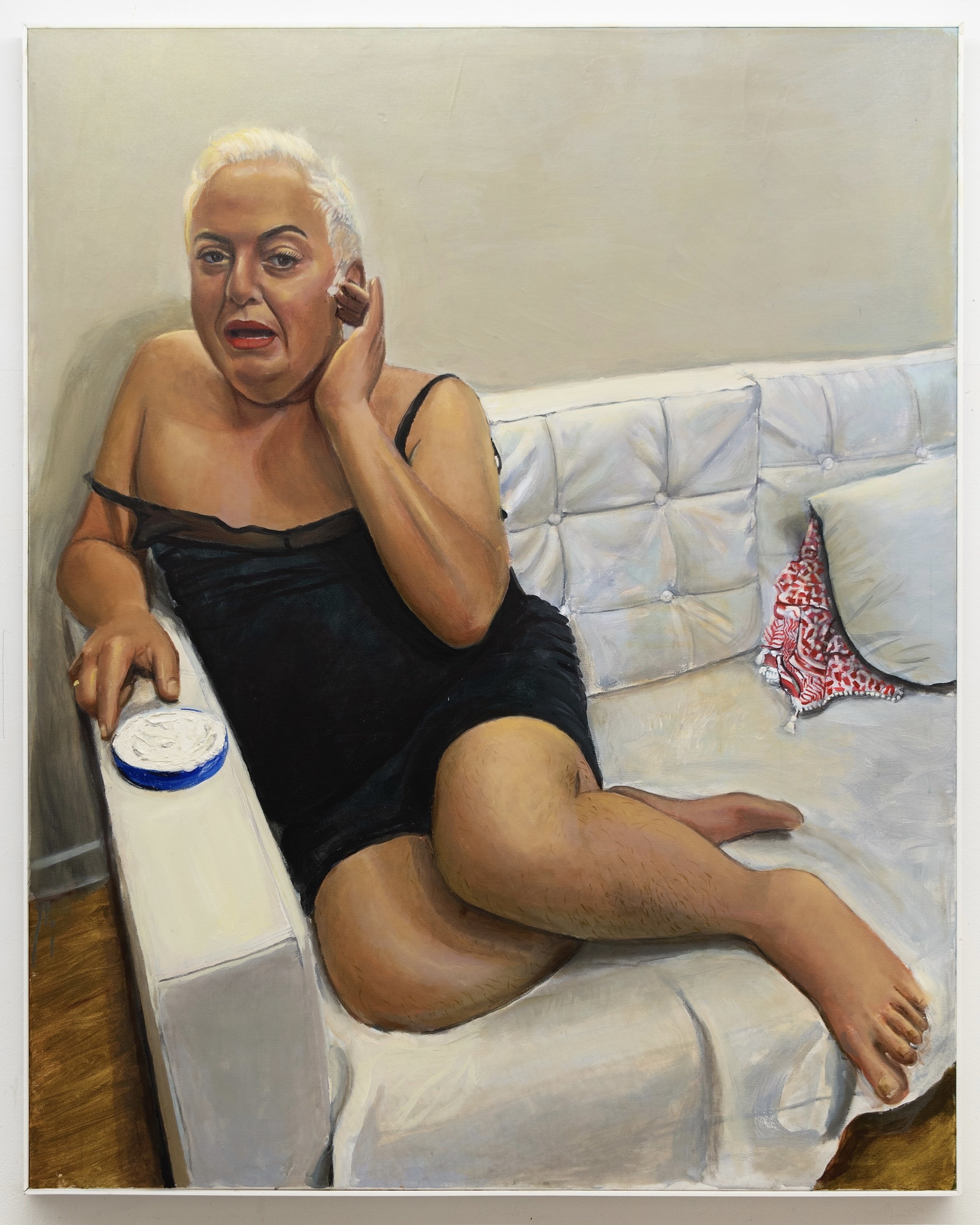 A portrait of Palestinian drag queen Sultana shows them applying Nivea on a couch after performing. A blue Nivea tub sits nearby, while a red-and-white keffiyeh peeks from behind a pillow, symbolizing tensions between cultural and queer identity.