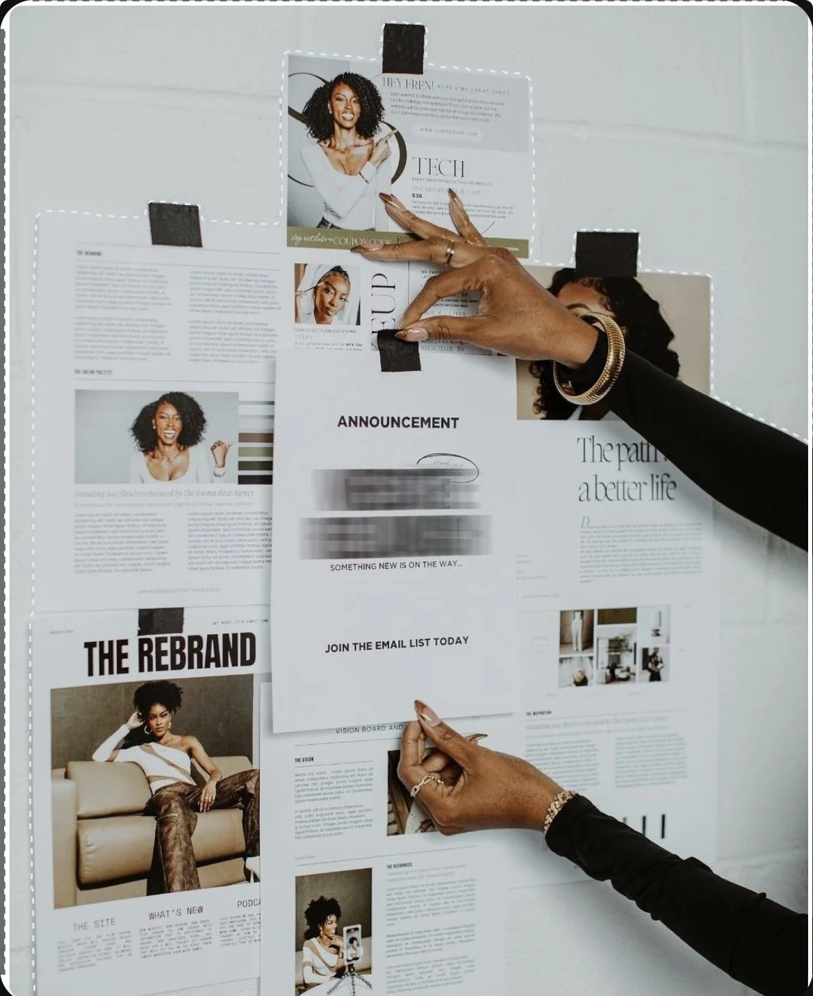 Person taping a newspaper or magazine page on a bulletin board, with multiple pages and advertisements visible.