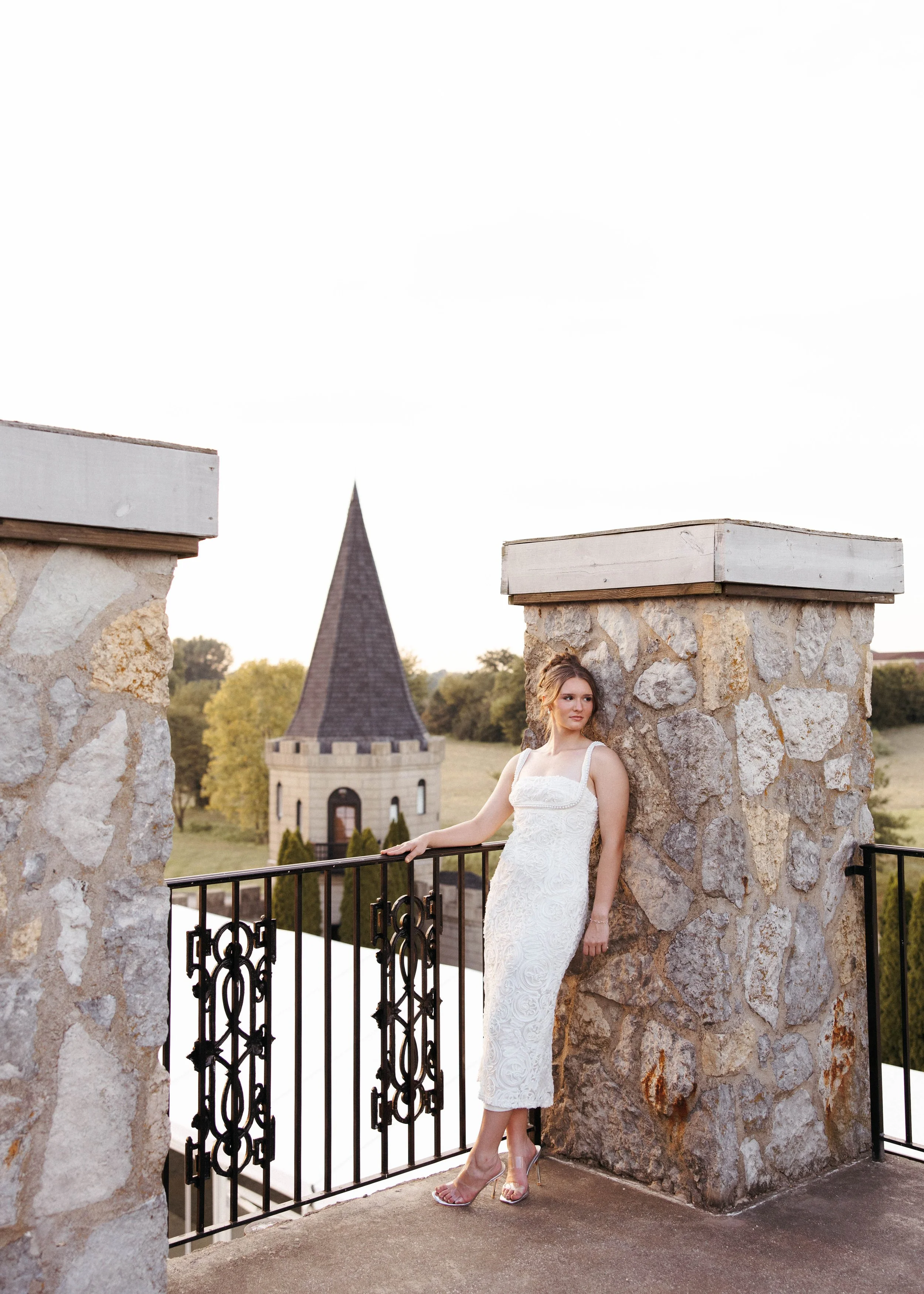 Elegant senior pictures at the Kentucky Castle in Versailles, KY, featuring a senior girl posing beside the castle’s stone architecture and iron gate