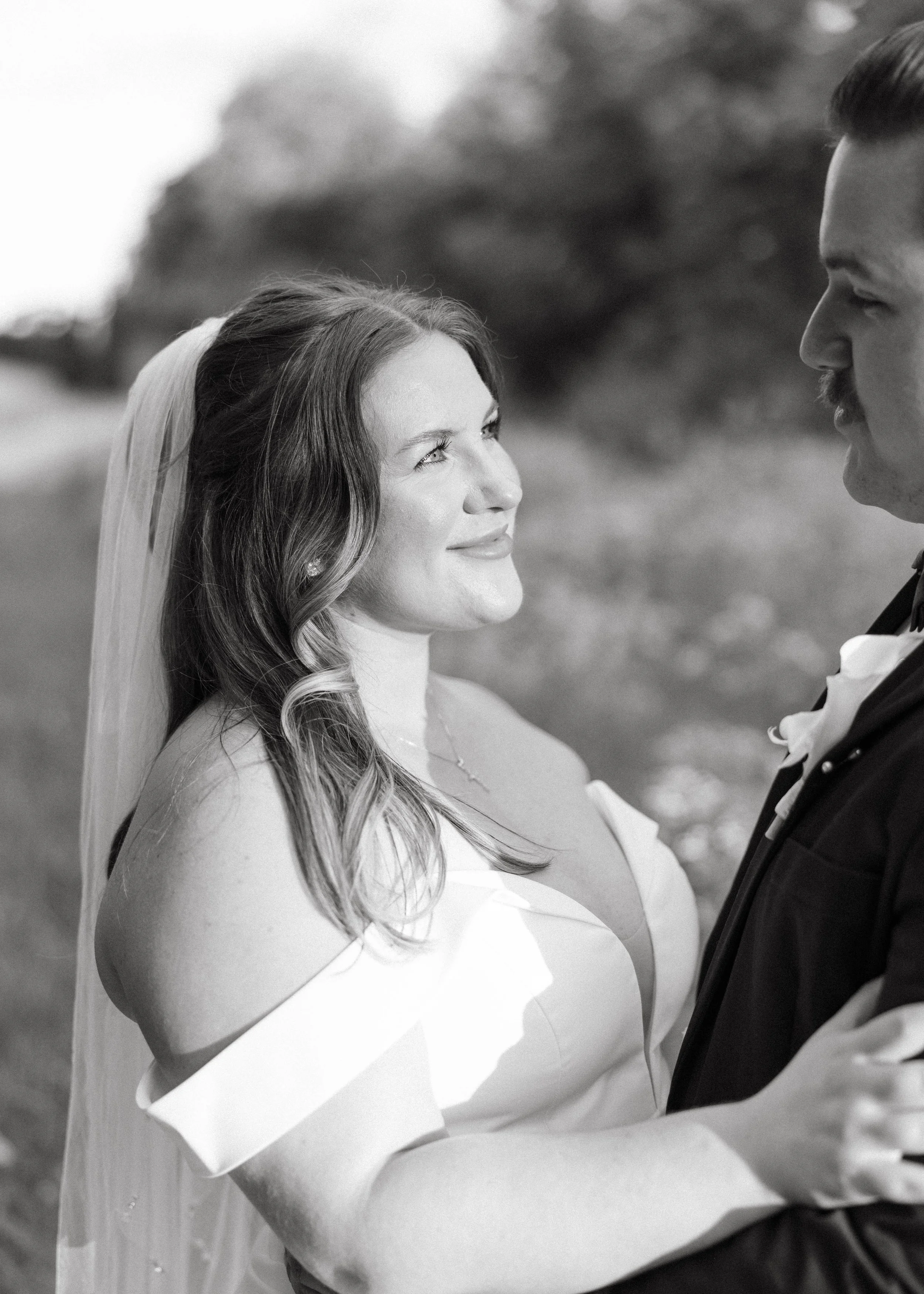 Bride is gazing into her husband's eyes while her veil falls softly behind her