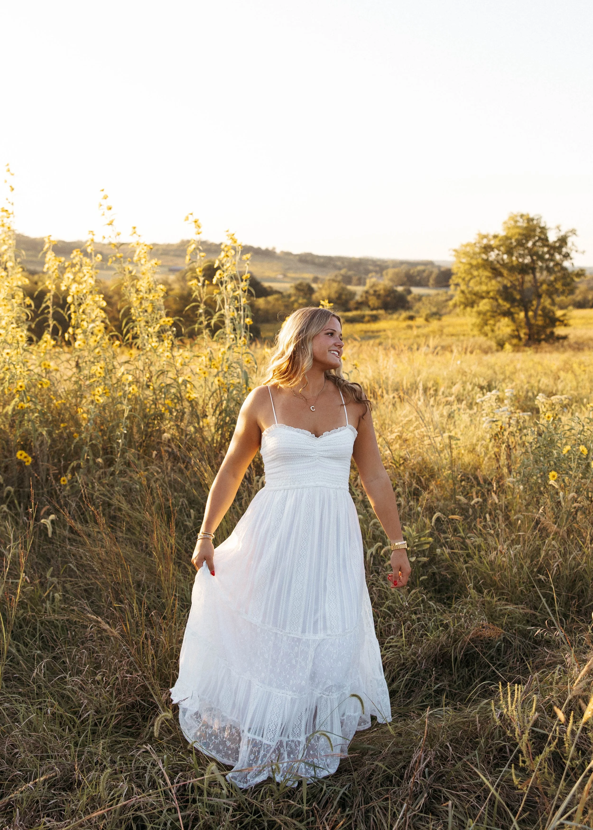Golden hour senior pictures at Shaker Village in Kentucky, featuring a senior girl posing in a field with rolling hills in the background
