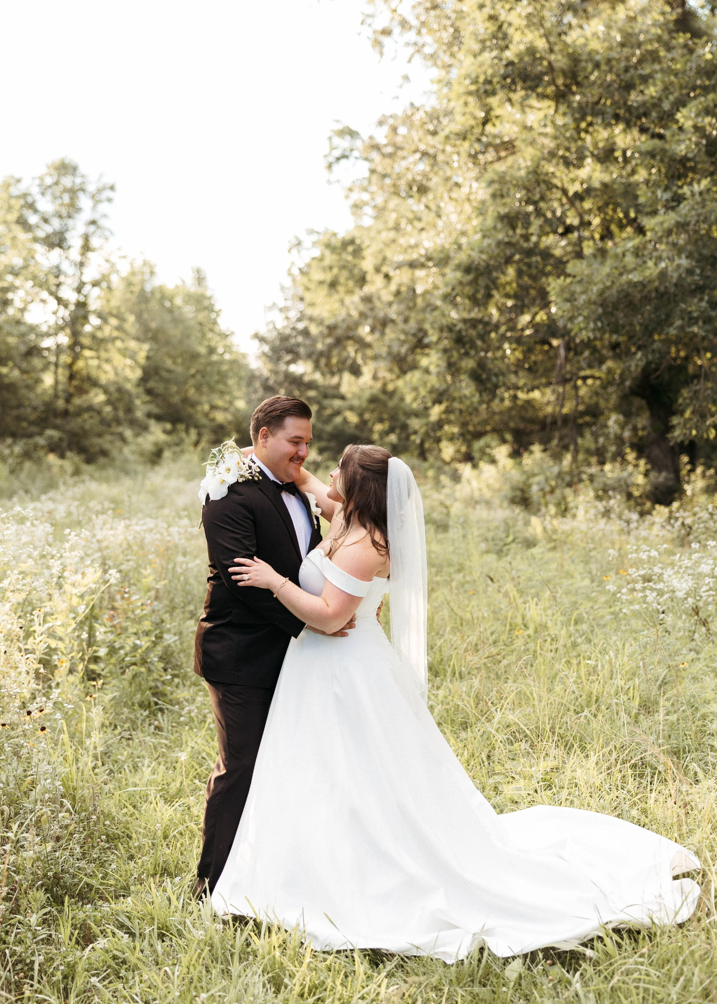 Bride and groom have their arms wrapped around each other while staring into each others eyes in a wildflower field in Kentucky