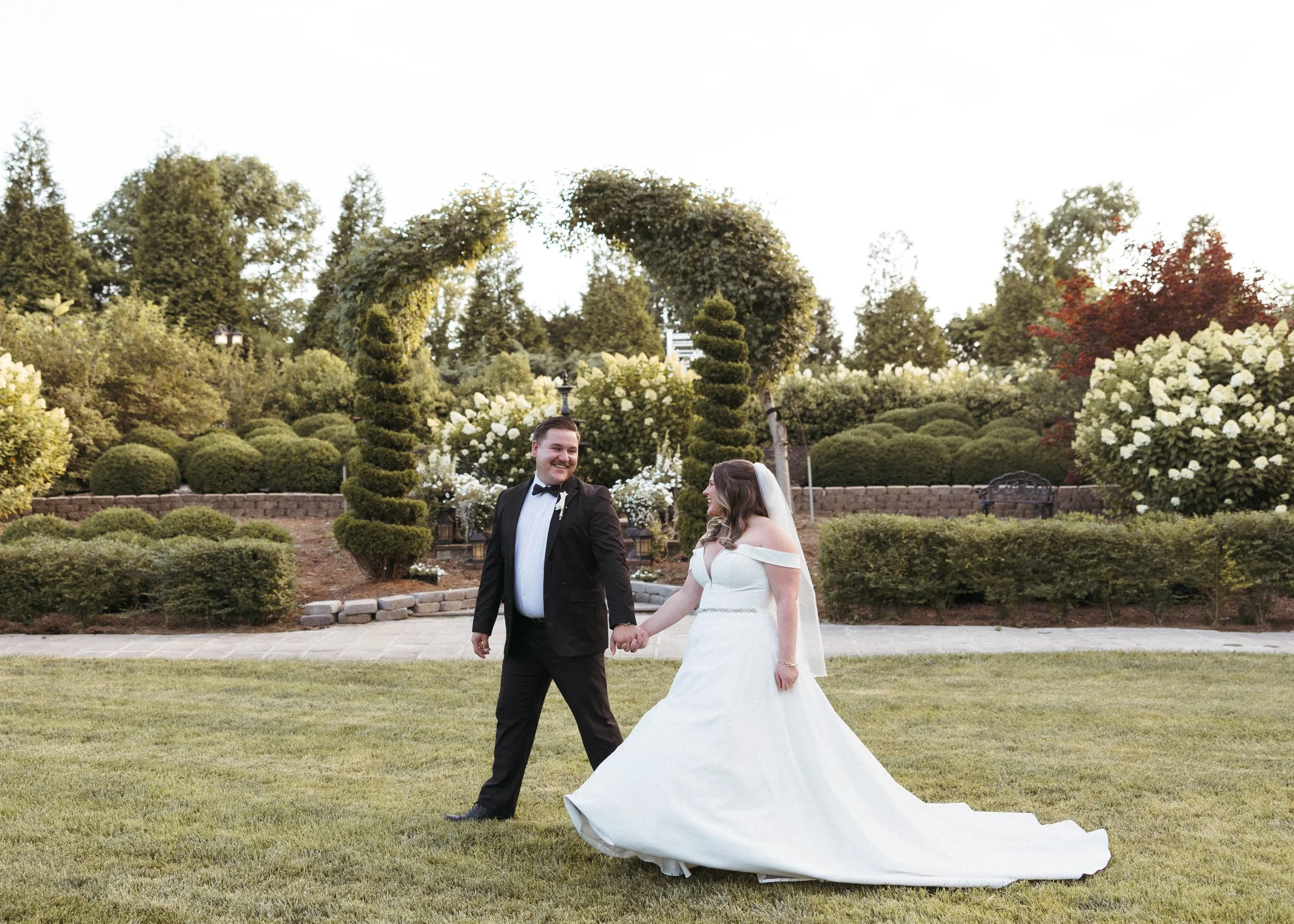 Groom leading his bride in the grass of a Kentucky wedding venue while looking back to admire his bride.