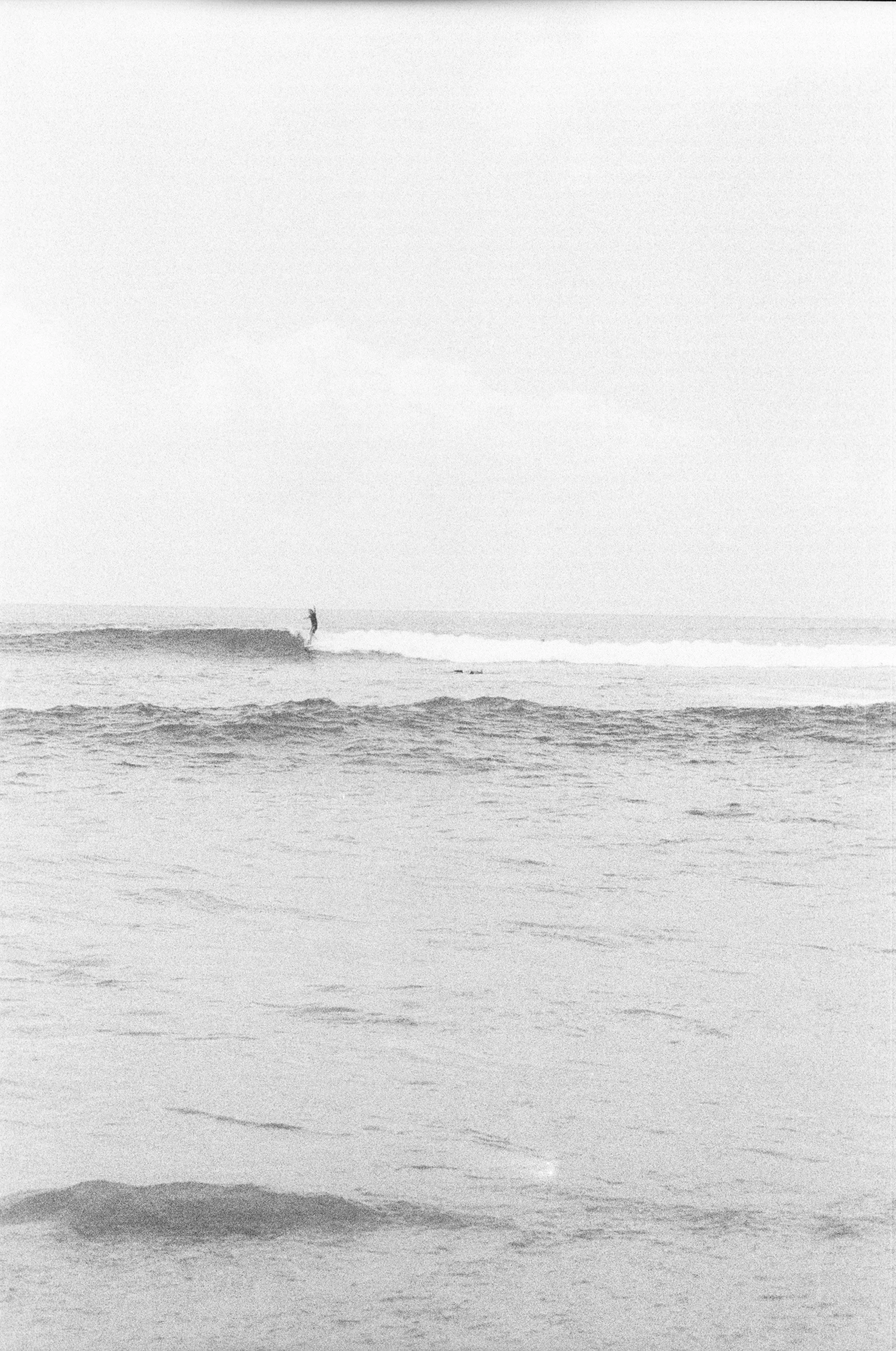 A person wakeboarding on the ocean during daytime with cloudy skies.